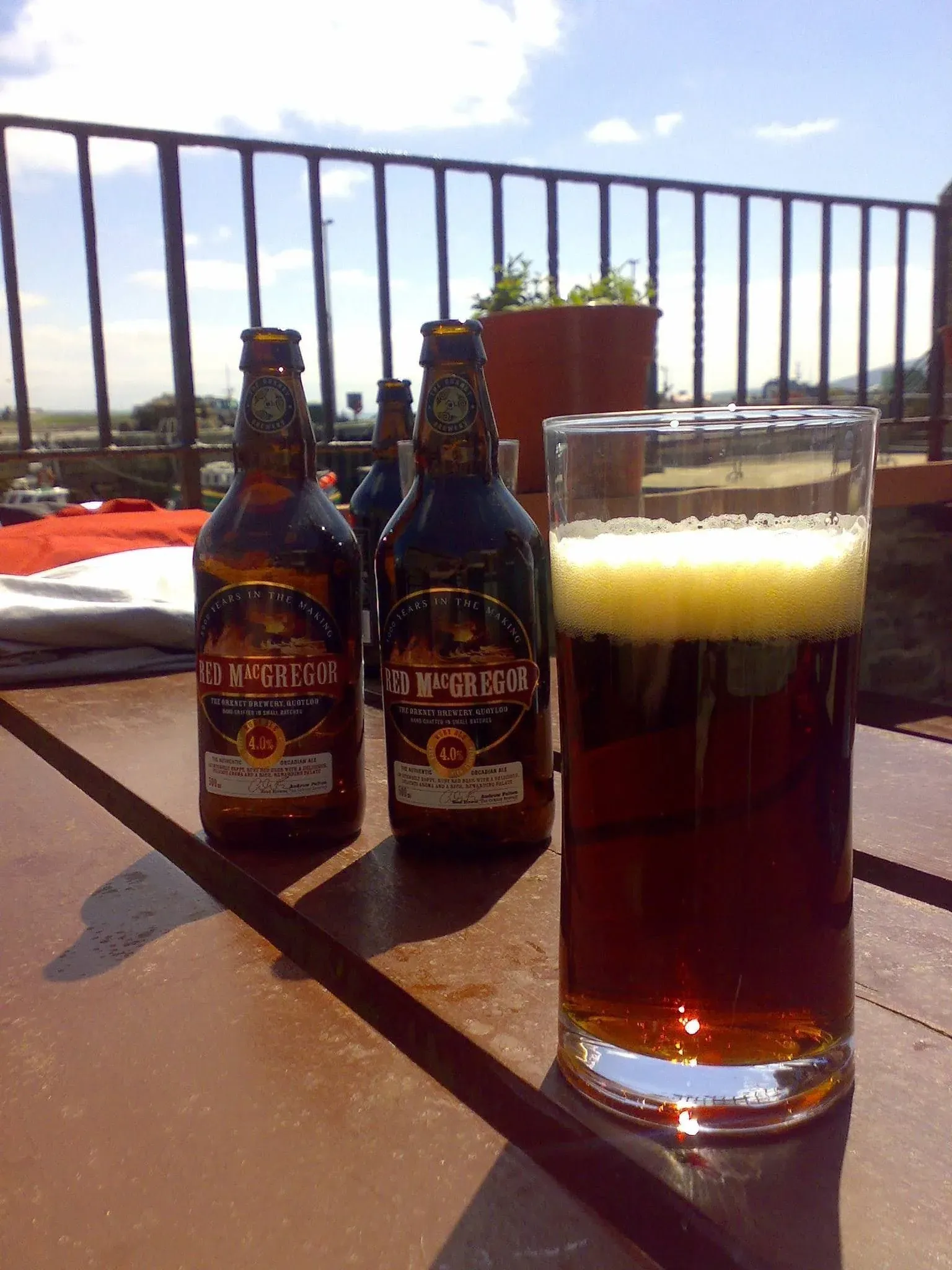 Red MacGregor beer bottles and glass on terrace overlooking landscape