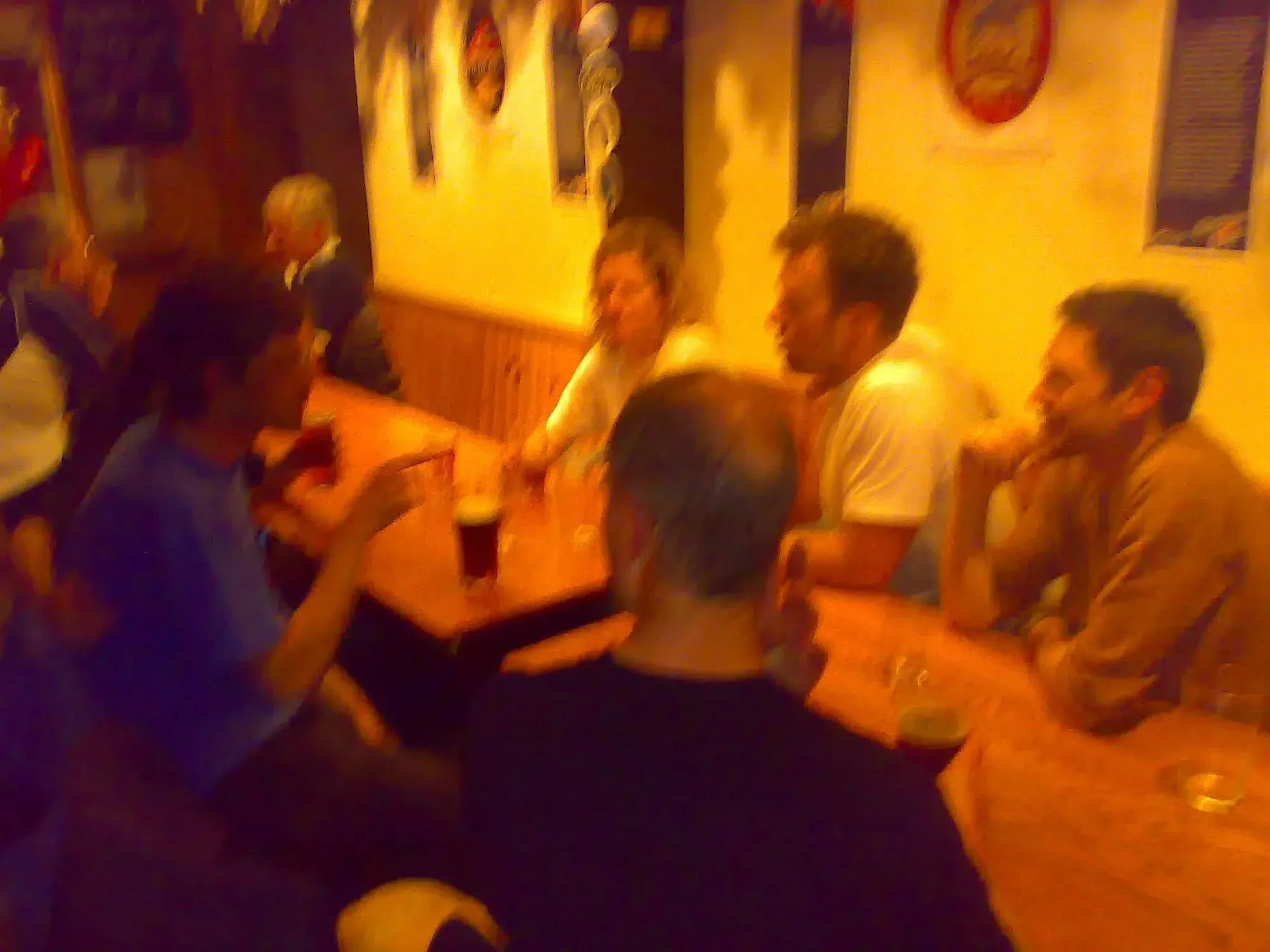 Group of people seated at long table indoors in warm yellow-orange lighting