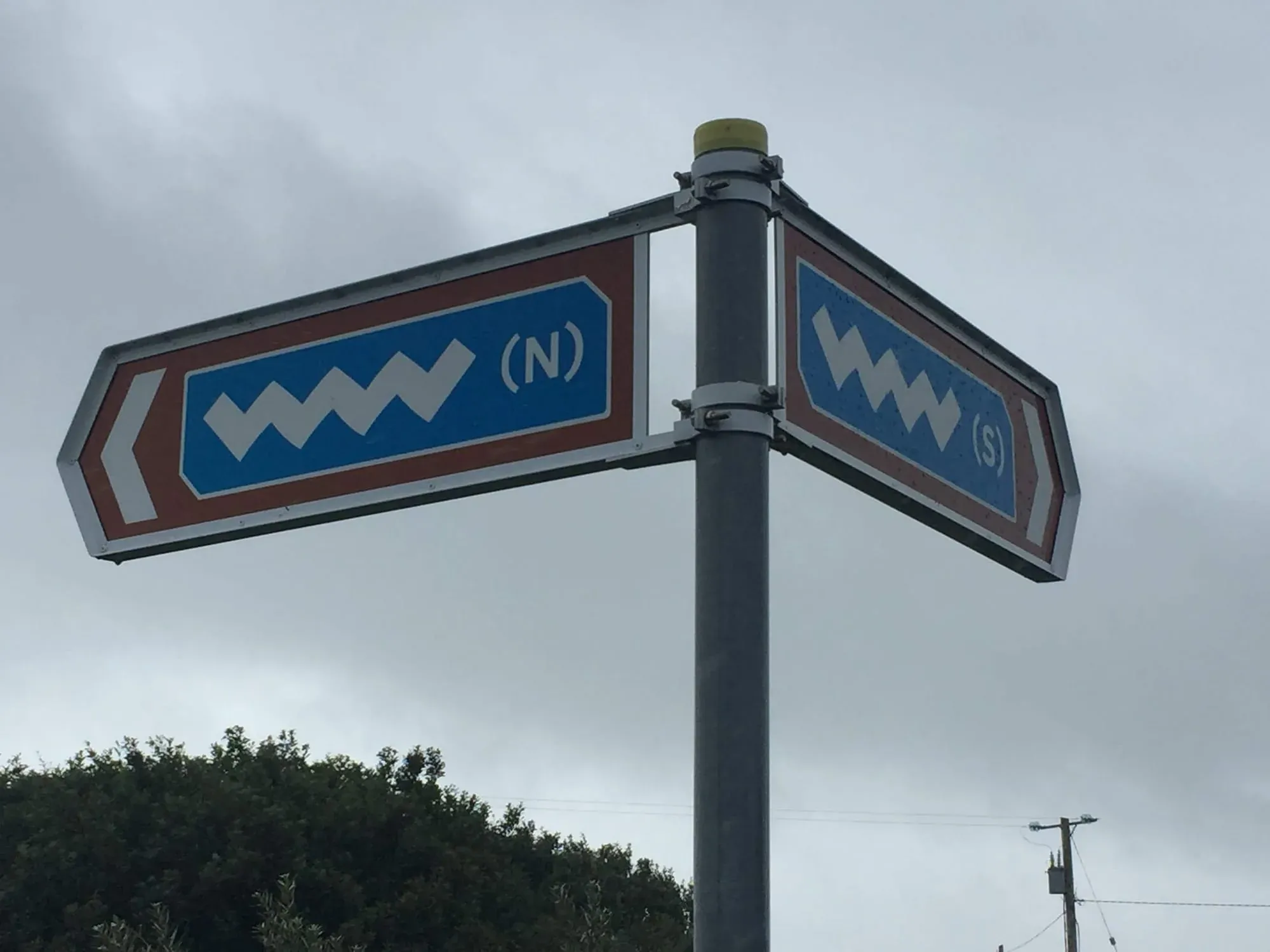 Directional road sign showing North and South arrows with chevron symbols on pole