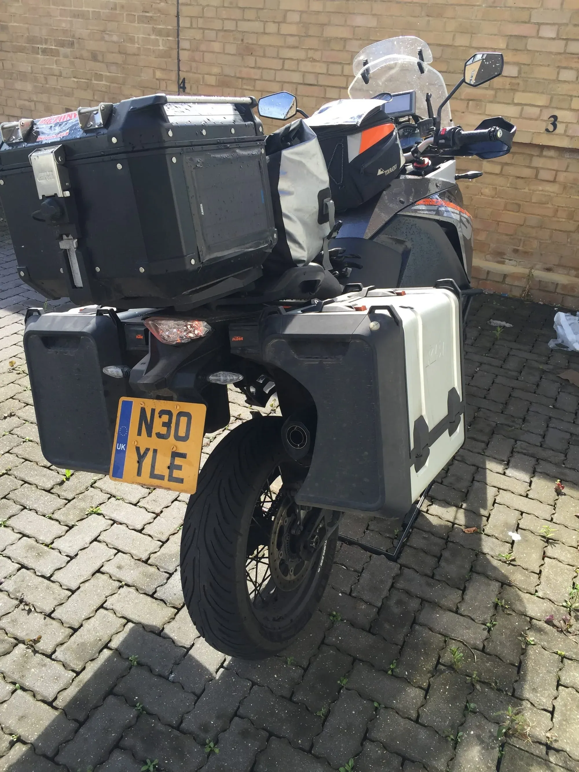 KTM motorcycle with sidecar and UK license plate parked against brick wall