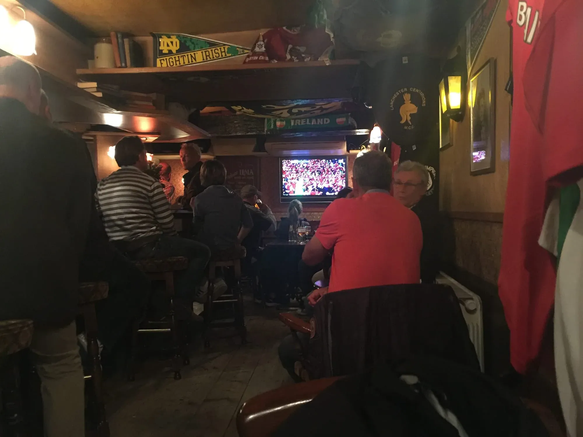 Interior of Irish pub with patrons watching sports on TV screen