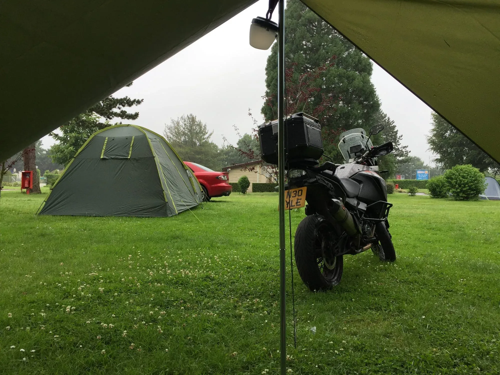 Motorcycle parked inside tent at campground with green grass field