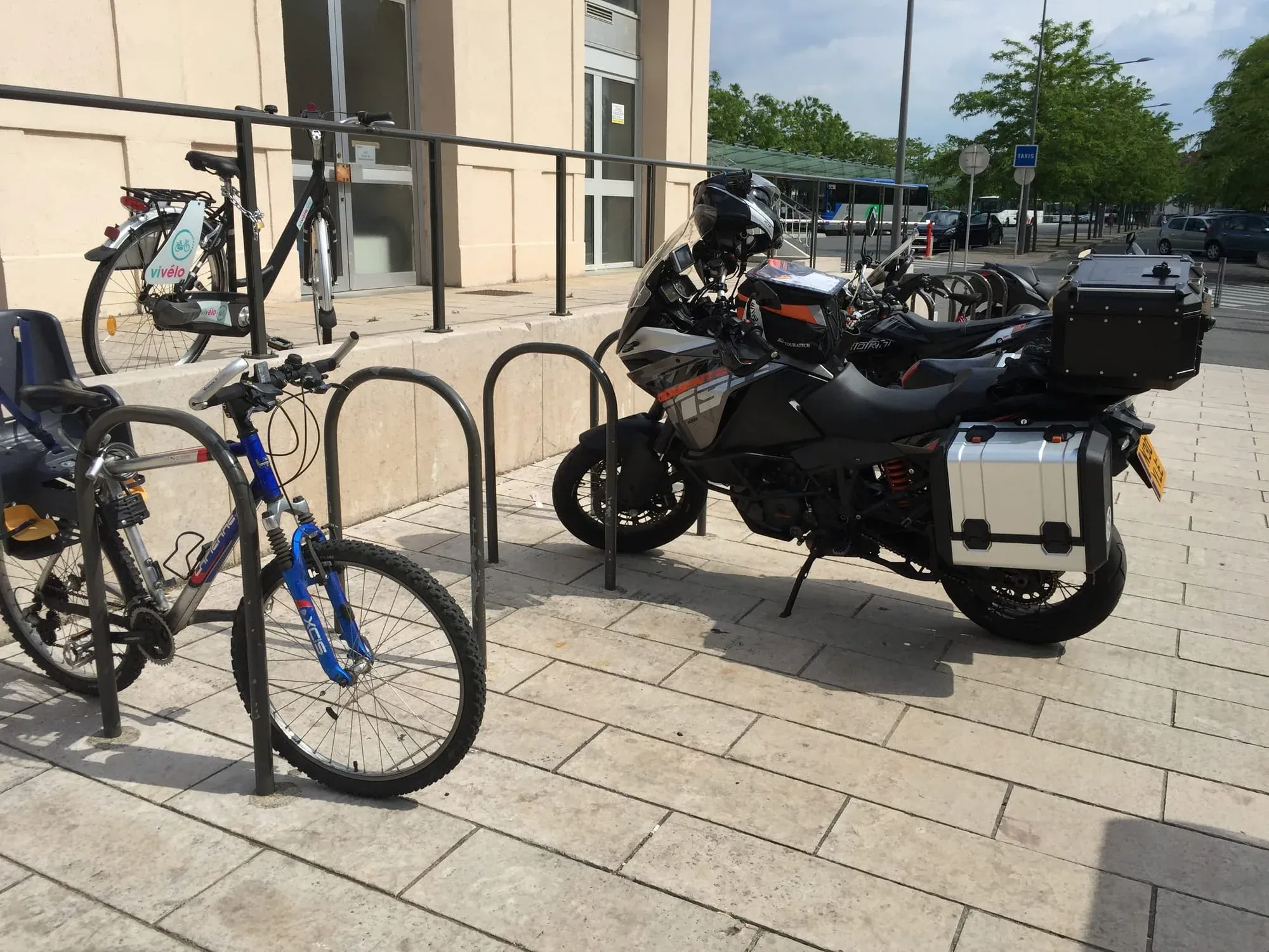 Motorcycles and bicycles parked at modern urban plaza in front of concrete building