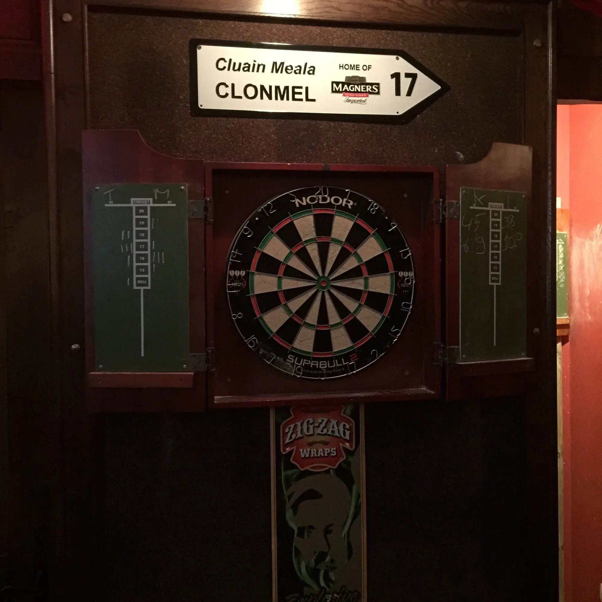 Dart board mounted on wall with Clonmel Ireland signage and Magners branding above
