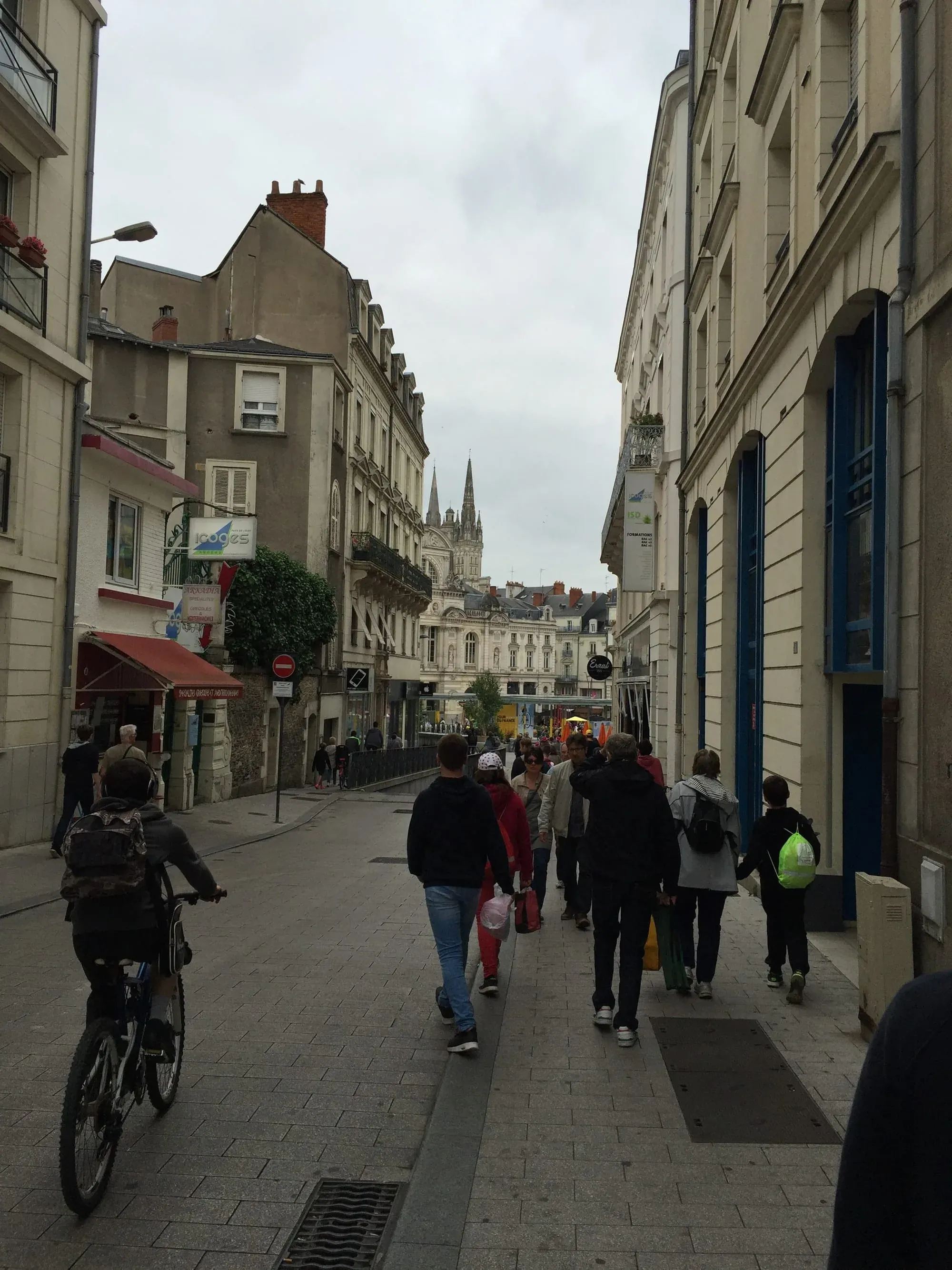 Pedestrian street in French town with shops and cathedral spire visible