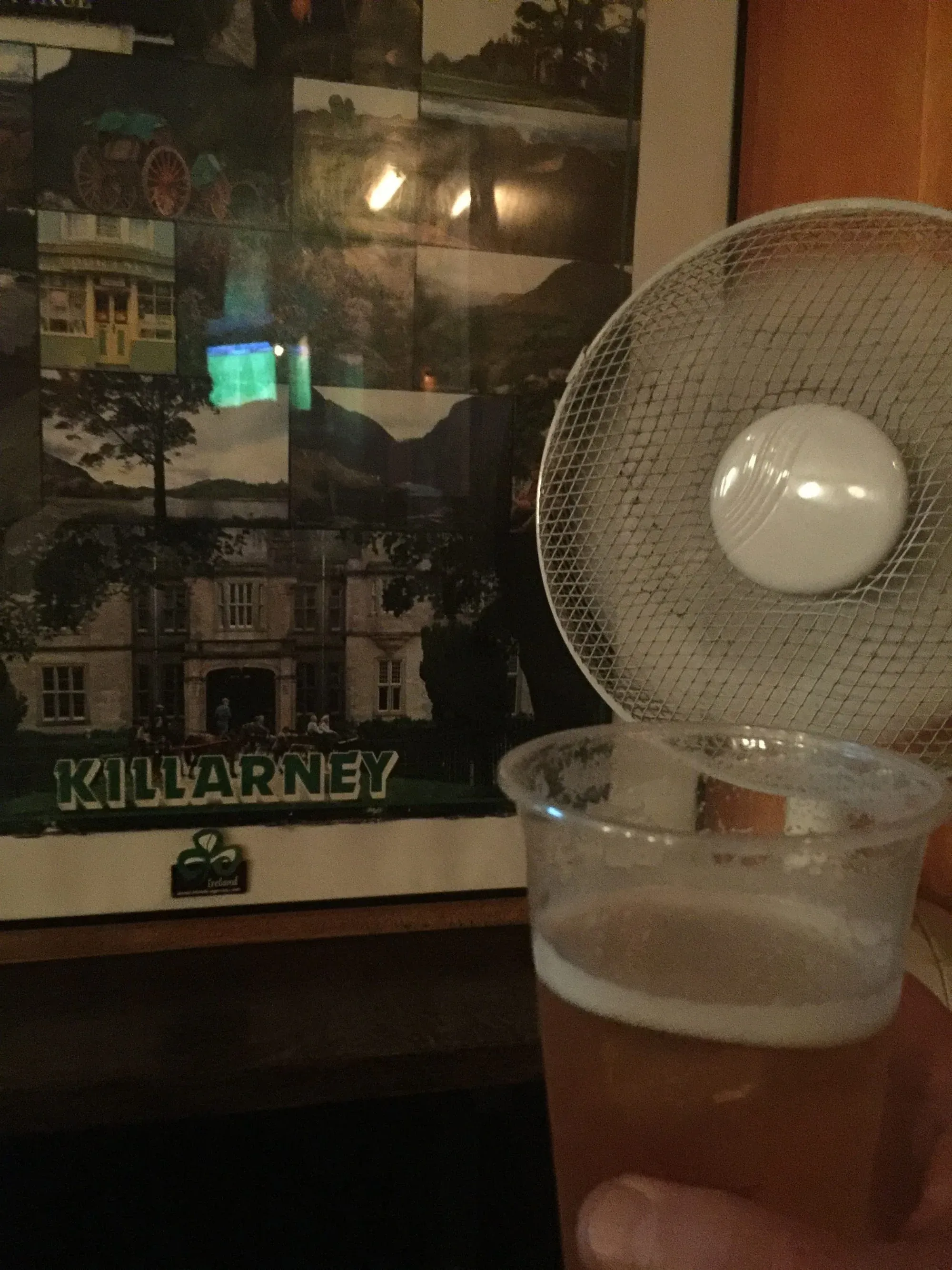 Killarney poster displayed indoors next to glass of beer with fan