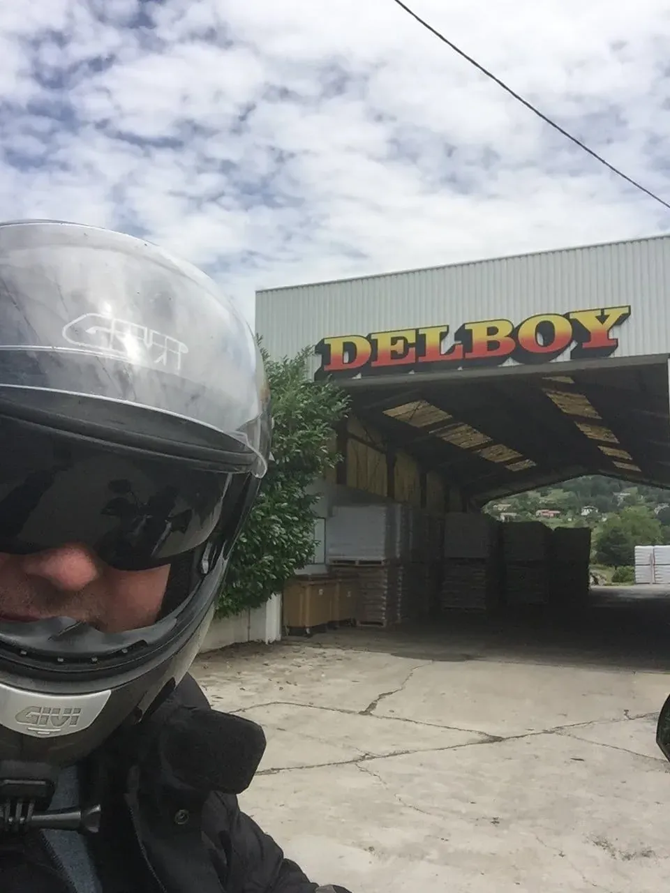 Motorcycle helmet in front of DelBoy establishment with countryside visible