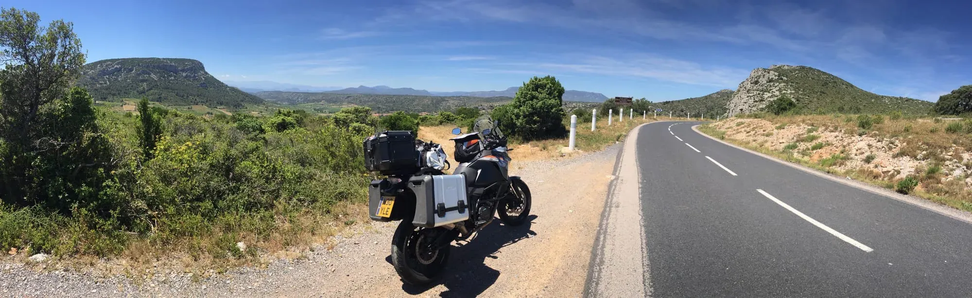 Motorcycle parked on dirt road with mountainous Mediterranean landscape backdrop