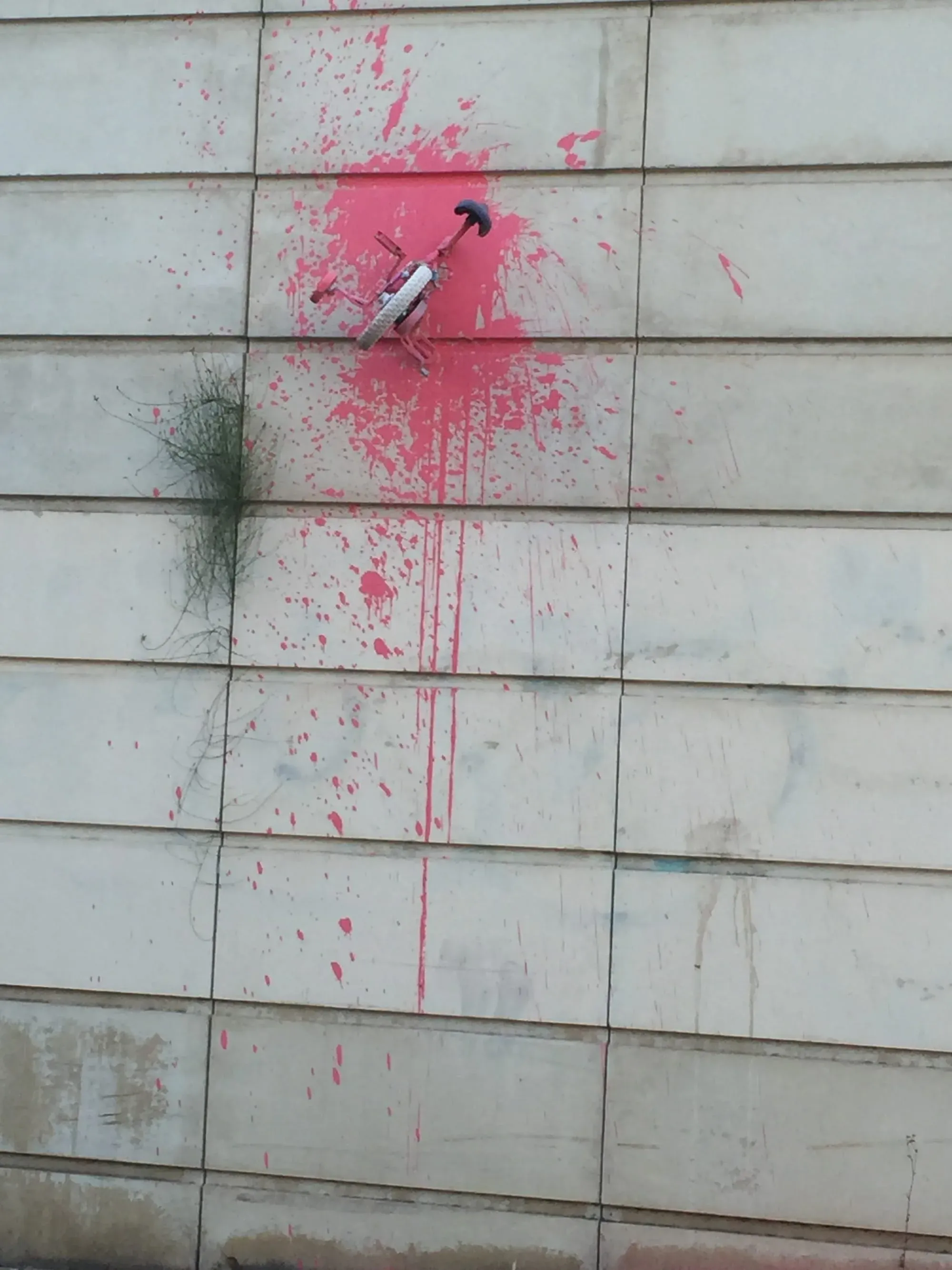 Pink spray paint arrow symbol on white tiled wall surface