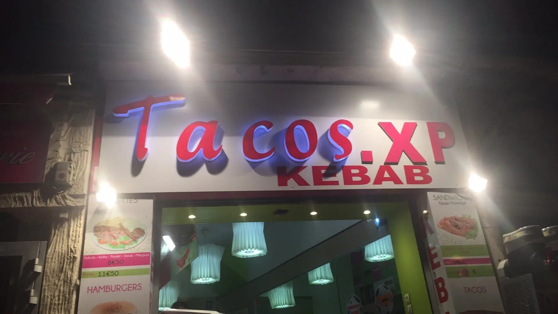 Tacos XP Kebab restaurant storefront illuminated at night with neon signage
