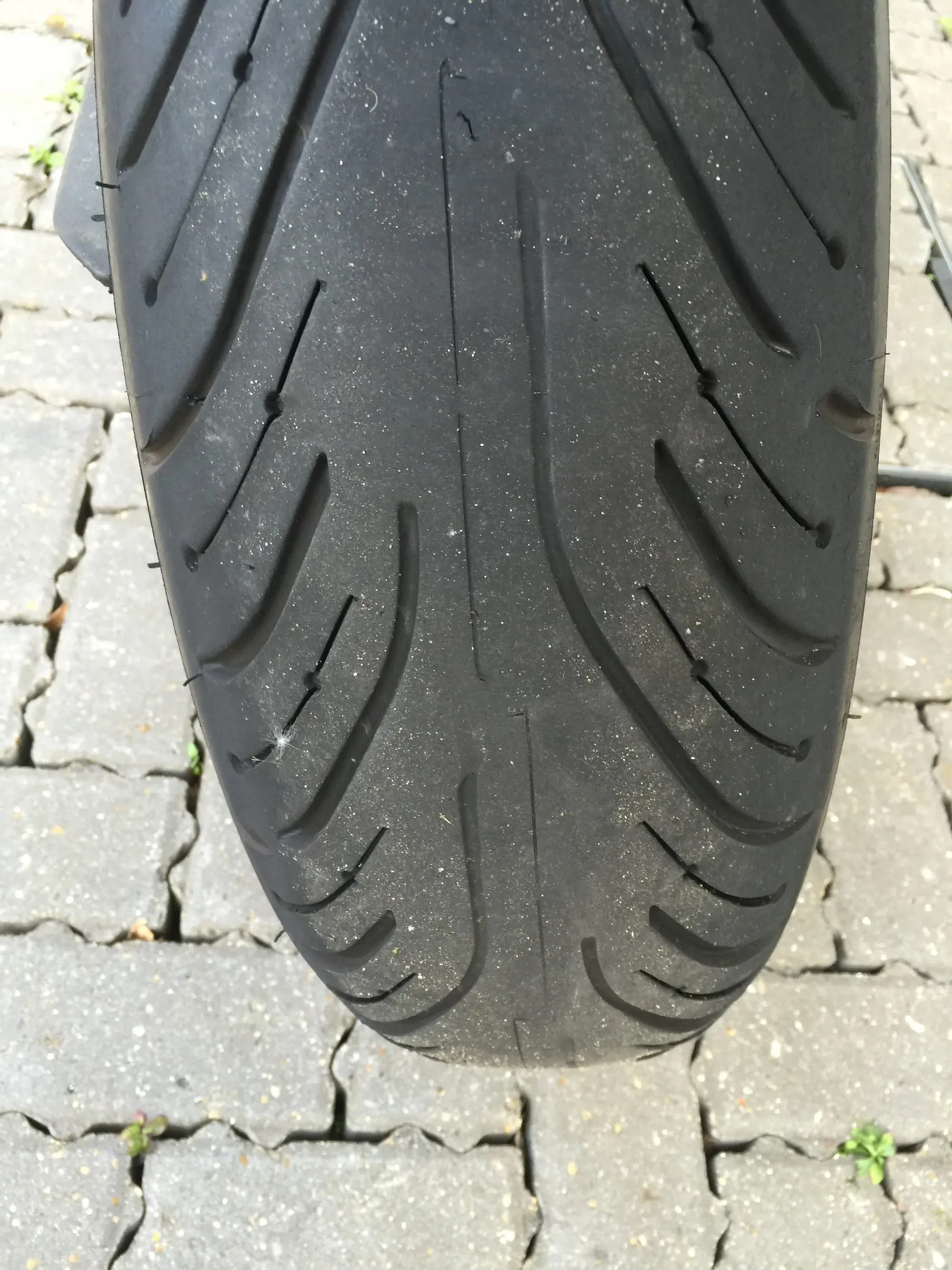 Close-up of motorcycle tire tread showing wear pattern on concrete surface