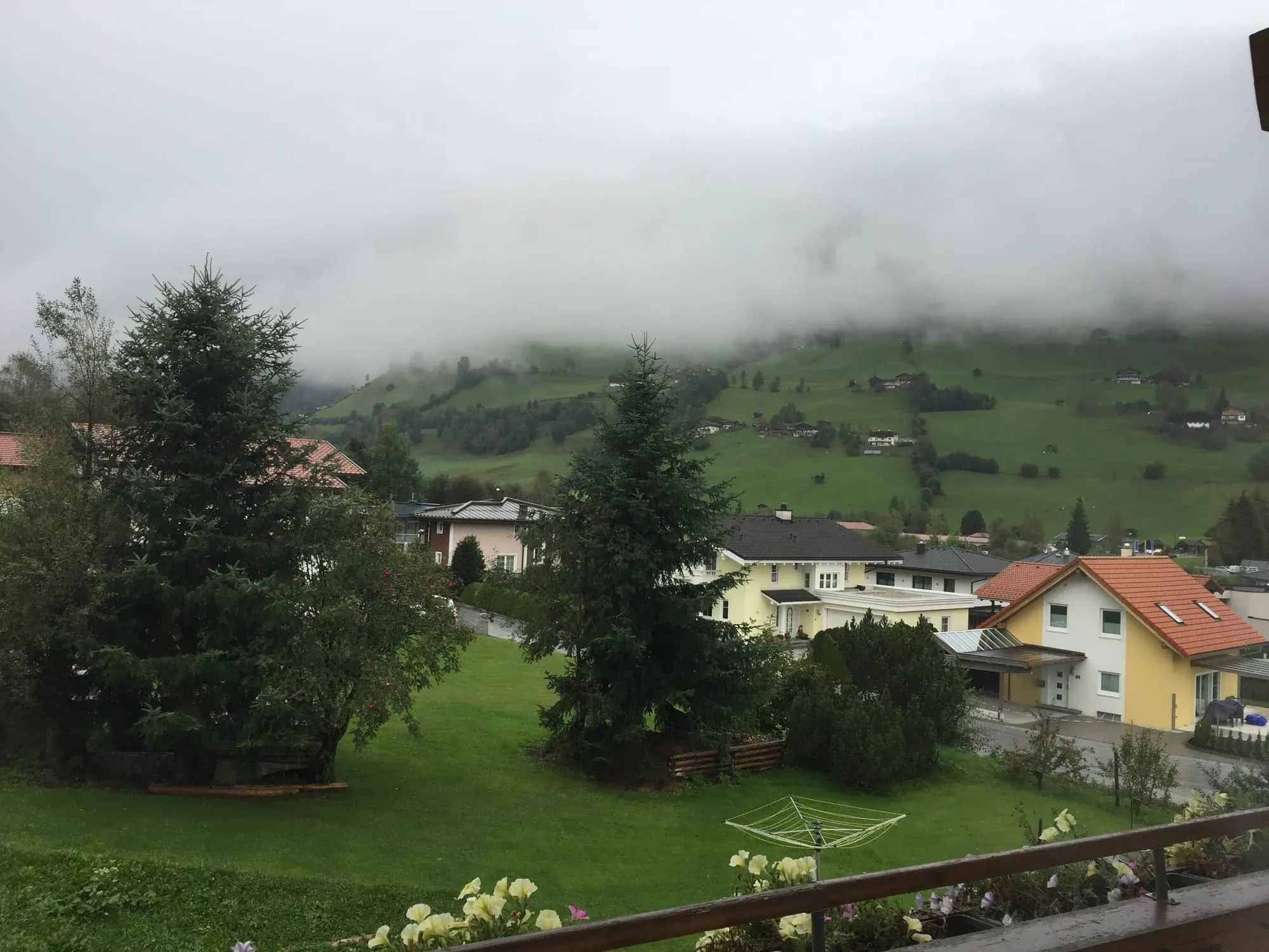 Alpine valley landscape with mist-covered mountains, green meadows and scattered houses