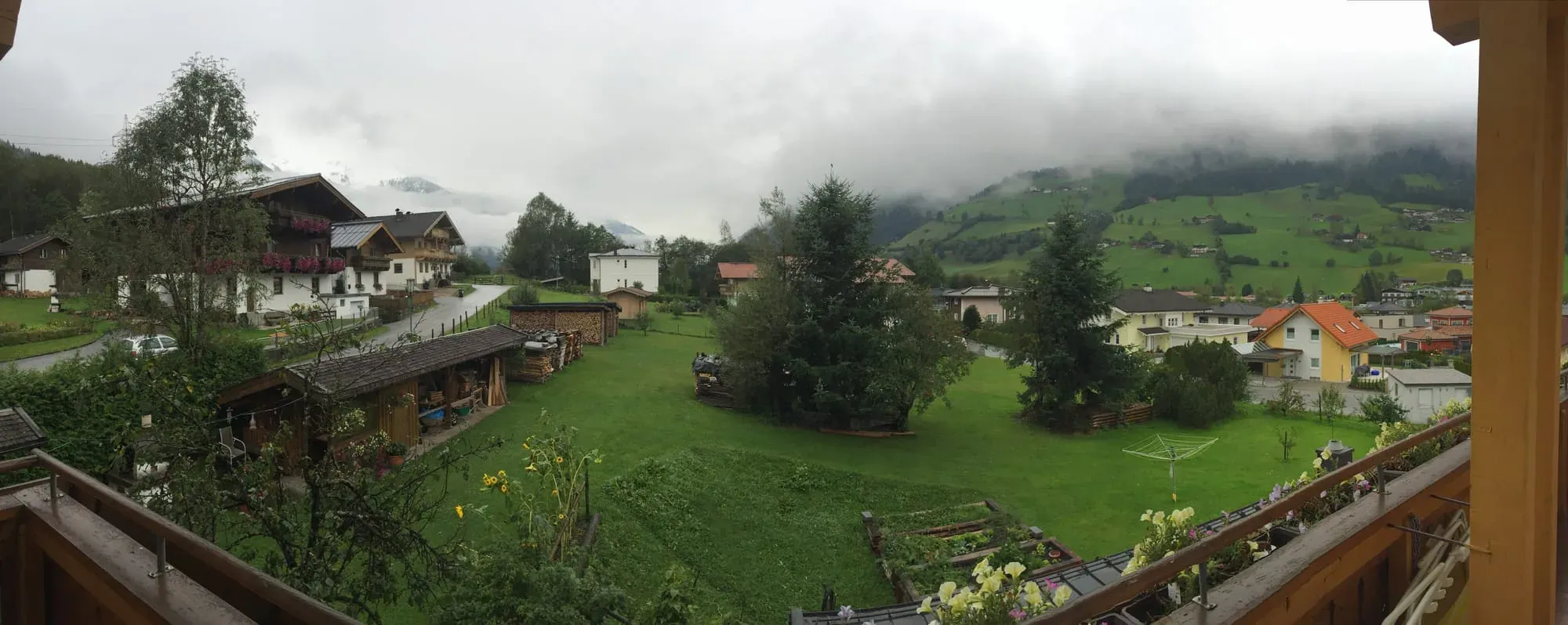 Panoramic view of misty Alpine village with traditional chalets and mountains in background