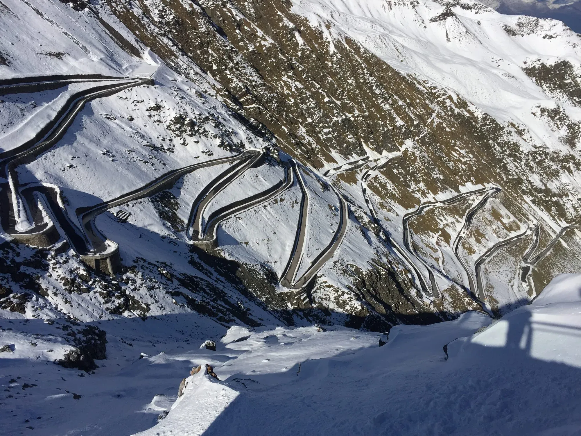 Aerial view of snow-covered mountain road with multiple hairpin turns