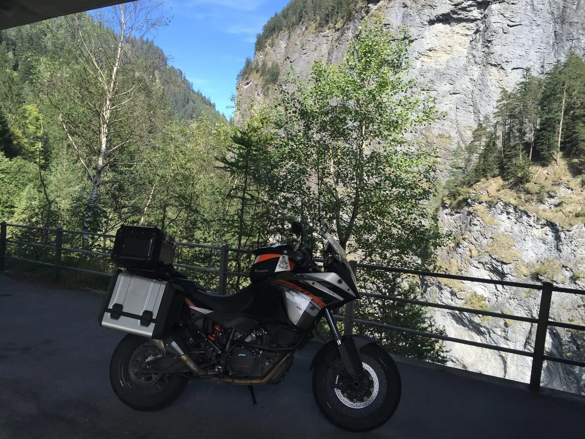 Red and black motorcycle with silver storage case parked at mountain overlook