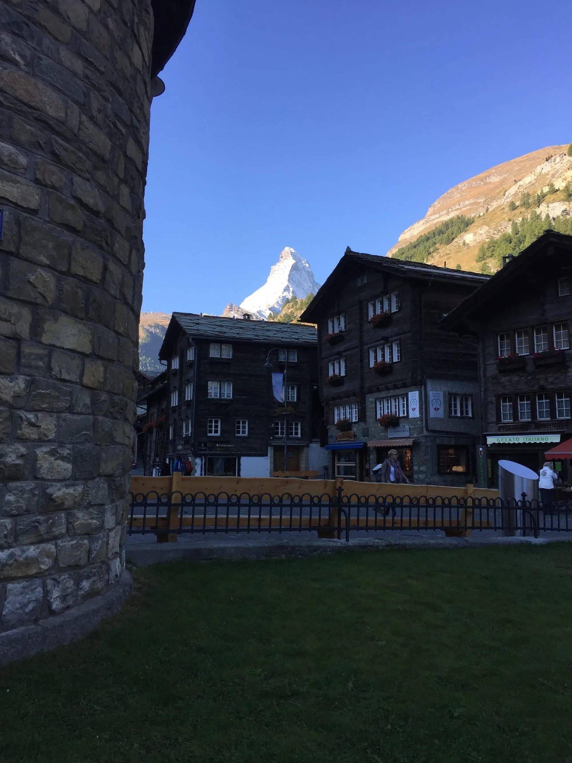 Alpine village with dark wooden chalets and snow-capped mountain peak in background