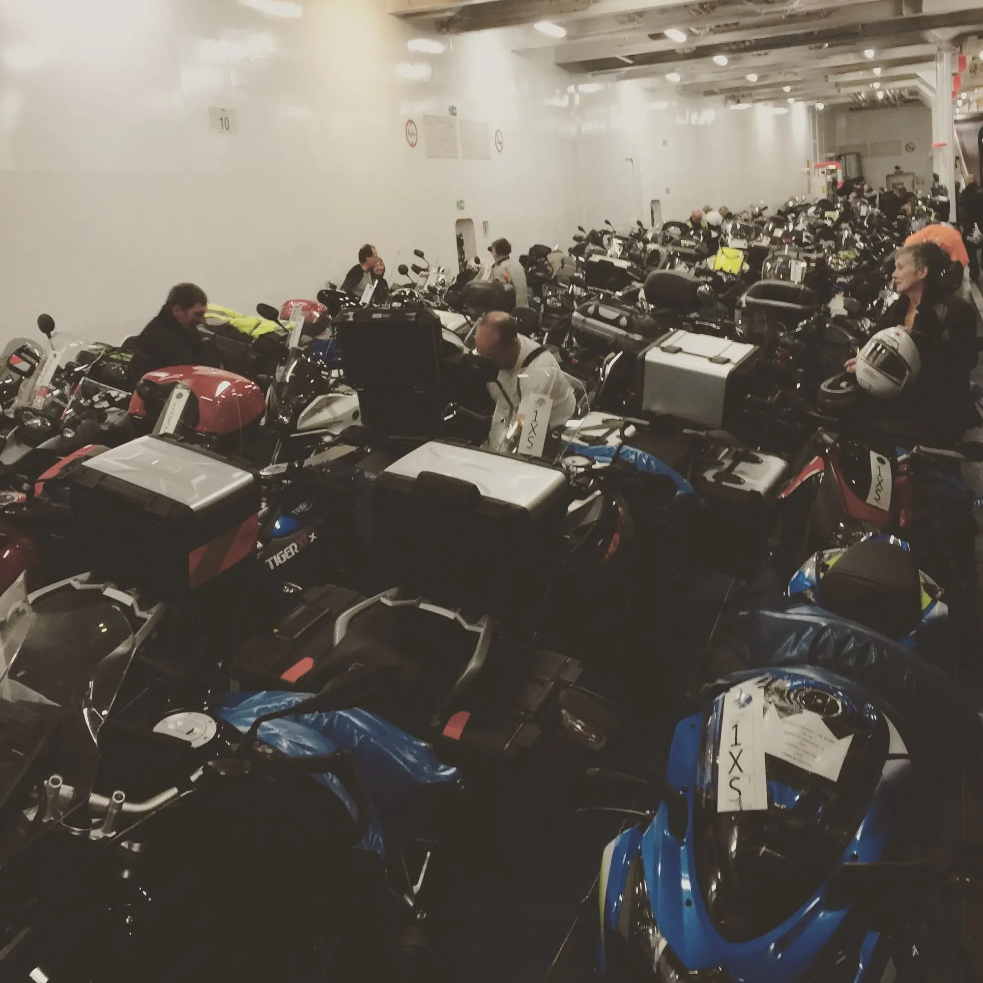 Large warehouse filled with many motorcycles on display with people walking around