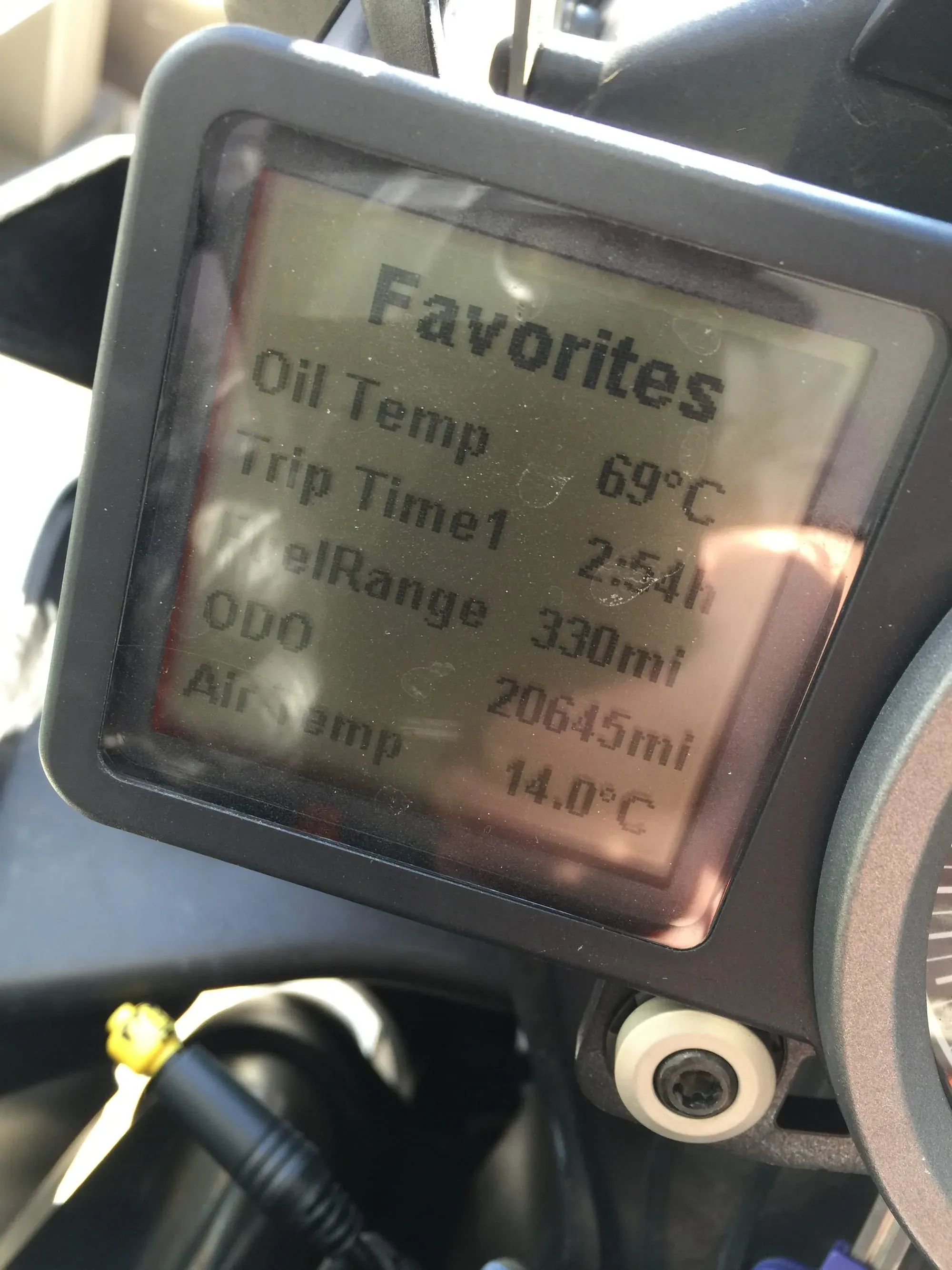 Motorcycle GPS display showing oil temp 69°C and trip data
