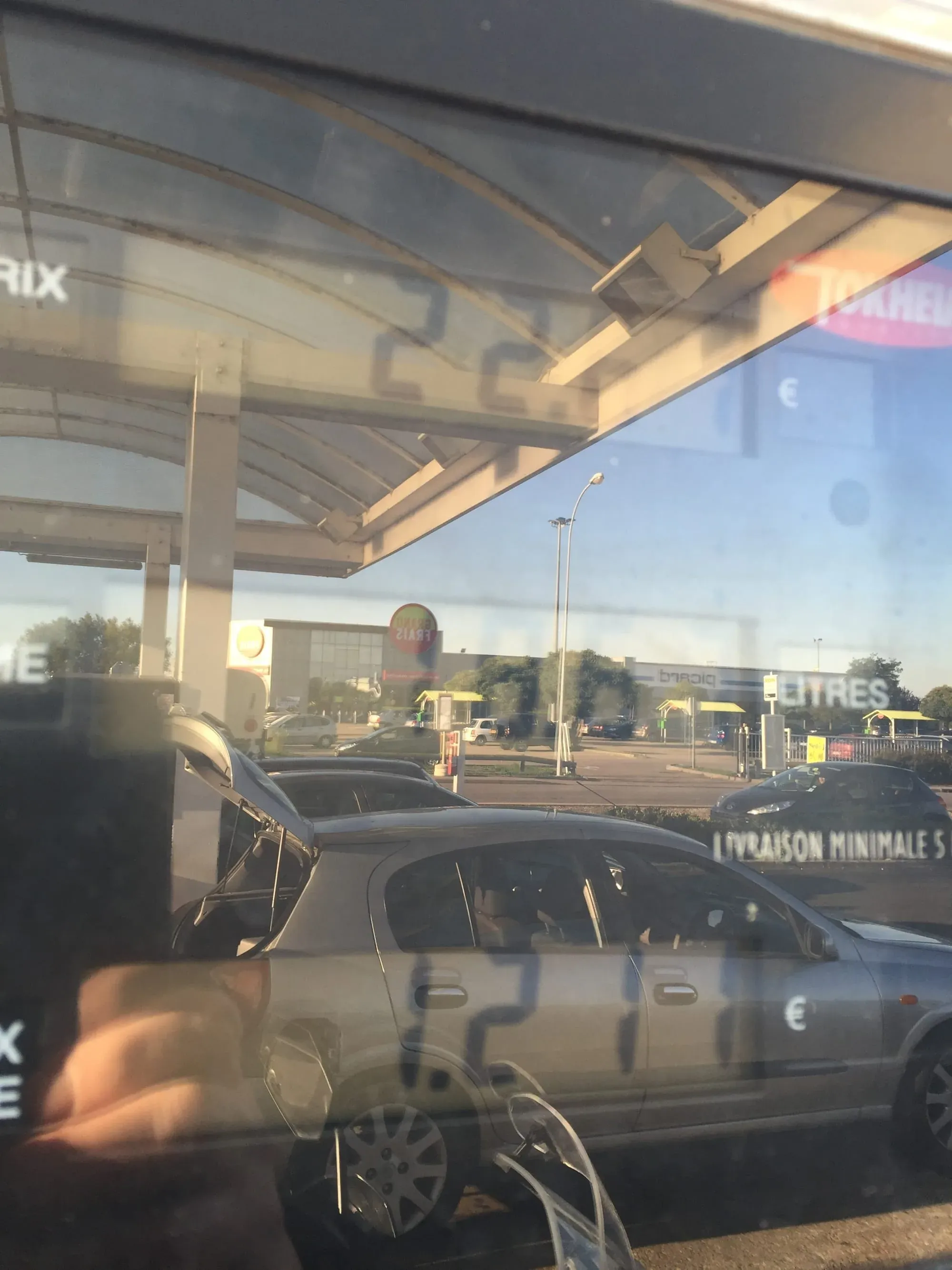 Gas station canopy with parked cars and commercial buildings visible