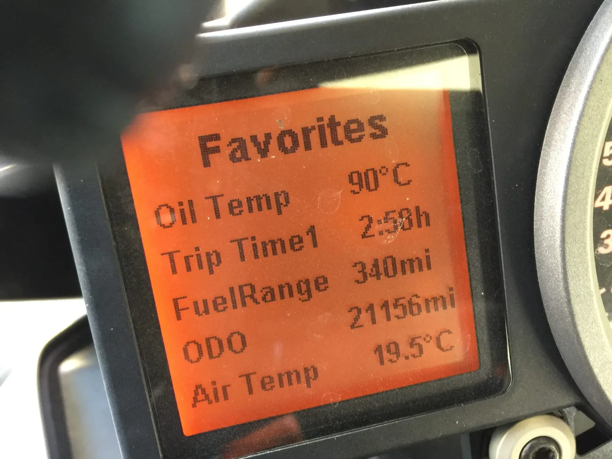 Motorcycle display with oil temp 90°C and trip statistics on orange screen