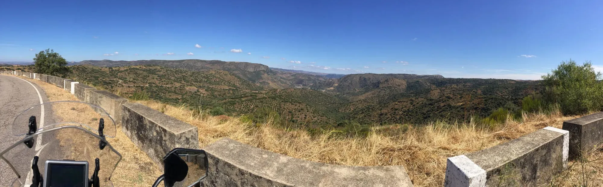 Scenic hillside overlook with stone wall and expansive valley landscape
