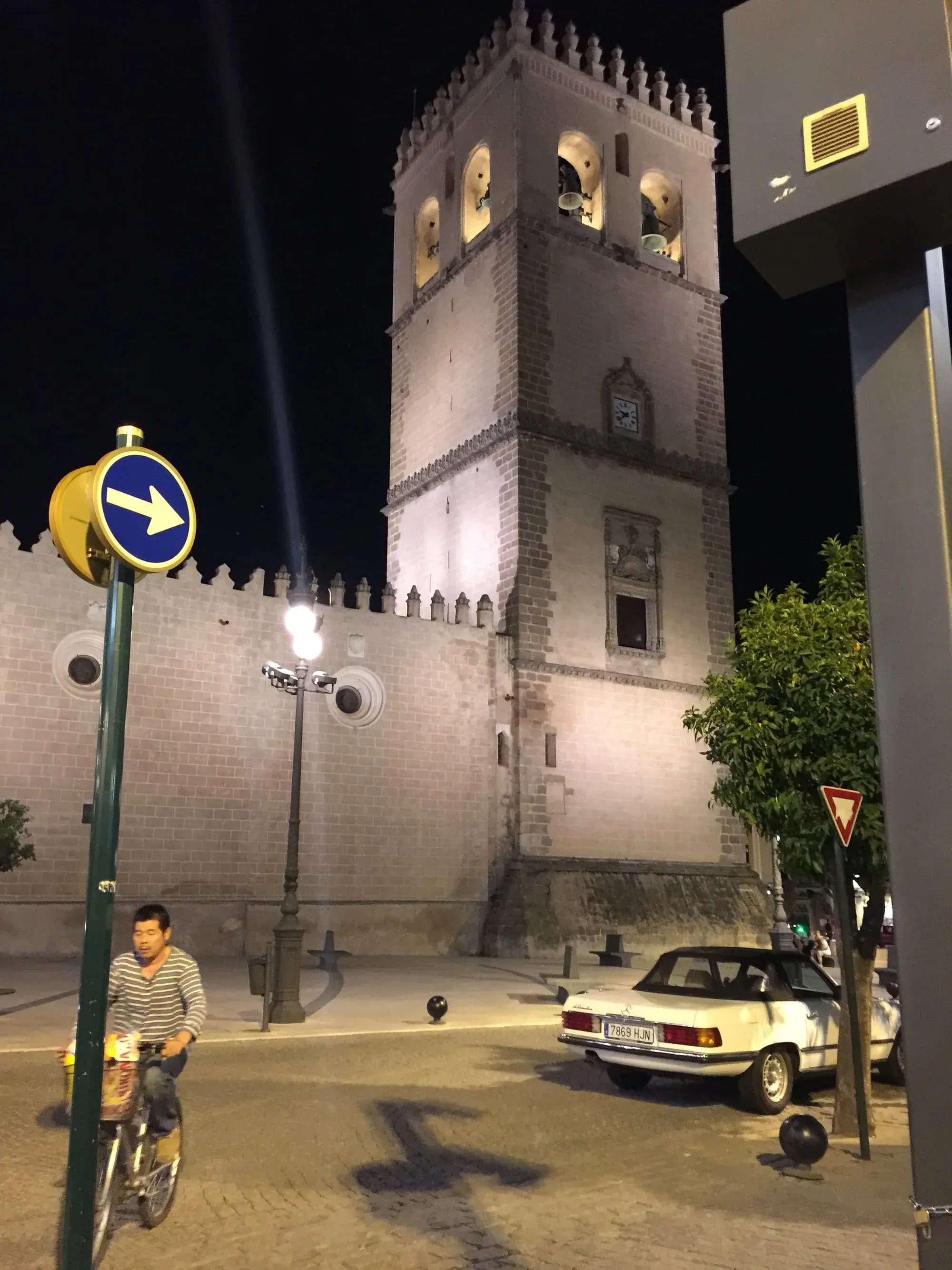 Historic brick tower illuminated at night with yellow car parked below