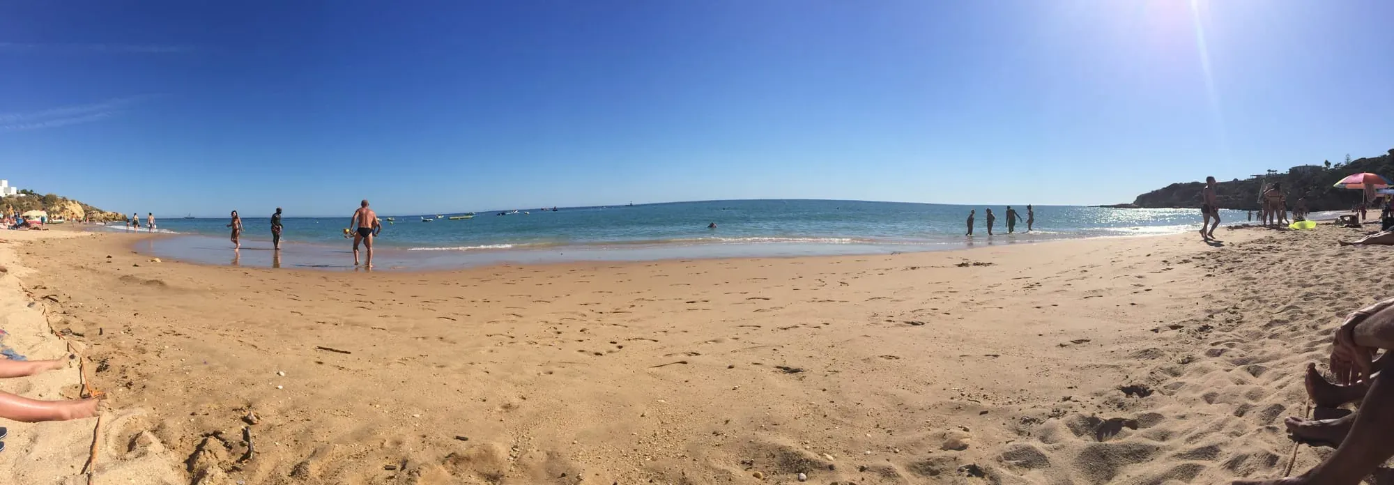 Sandy beach with clear blue water and people swimming and relaxing on shore