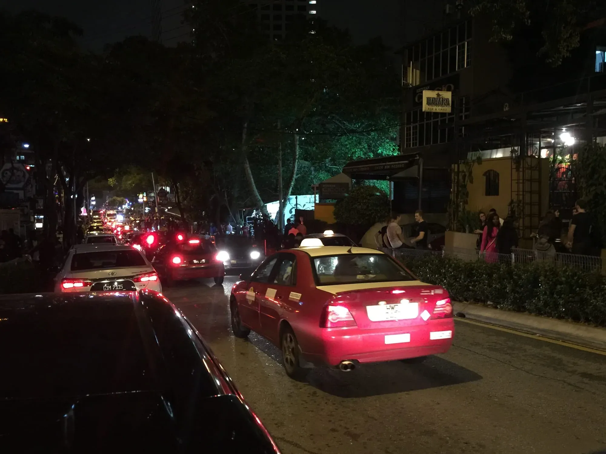 Multiple red taxis lined up on urban street at night