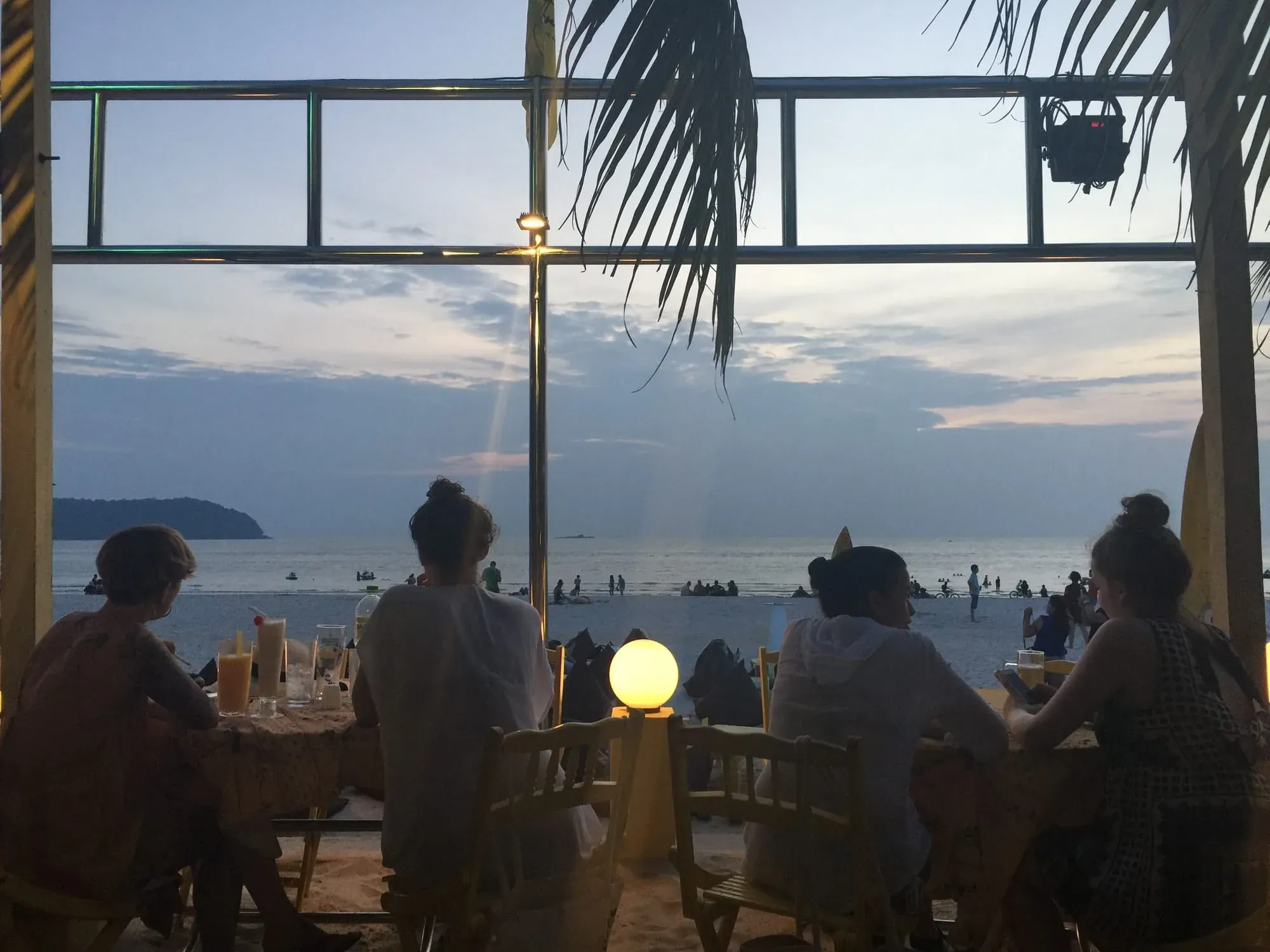 People dining at beachfront restaurant with ocean sunset view