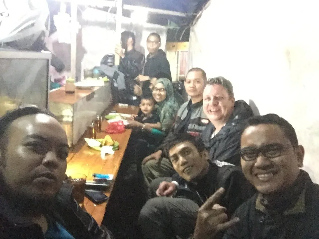 Group of people gathered around wooden table indoors for meal or meeting