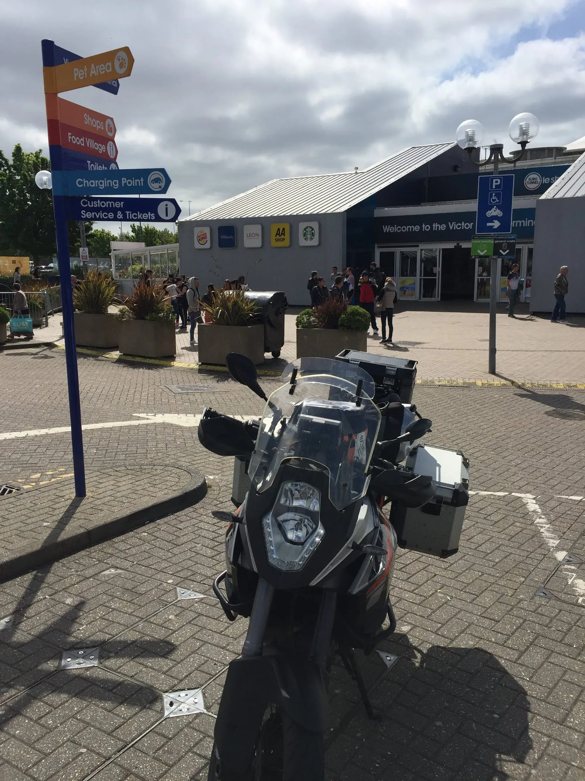 Black motorcycle parked at service station with directional signage and building entrance