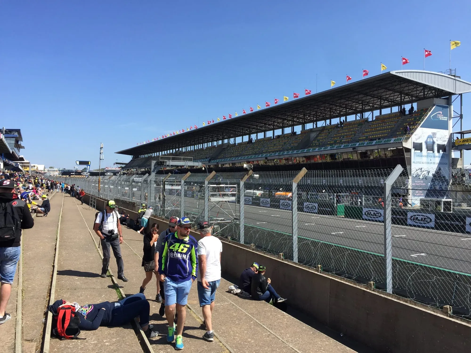 Racing spectators at circuit grandstand with safety fencing during daytime event
