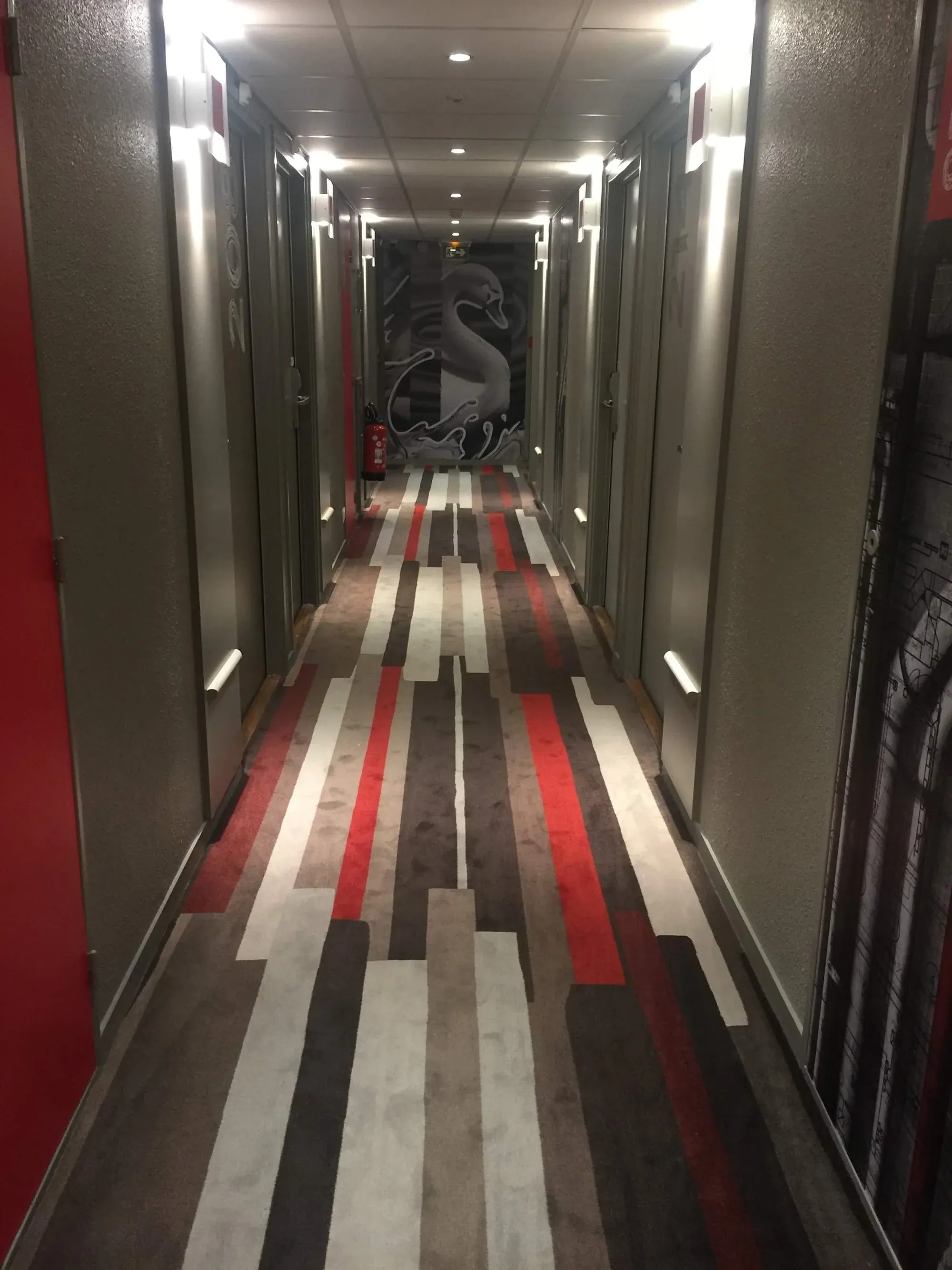 Modern hotel corridor with striped red white and gray floor design