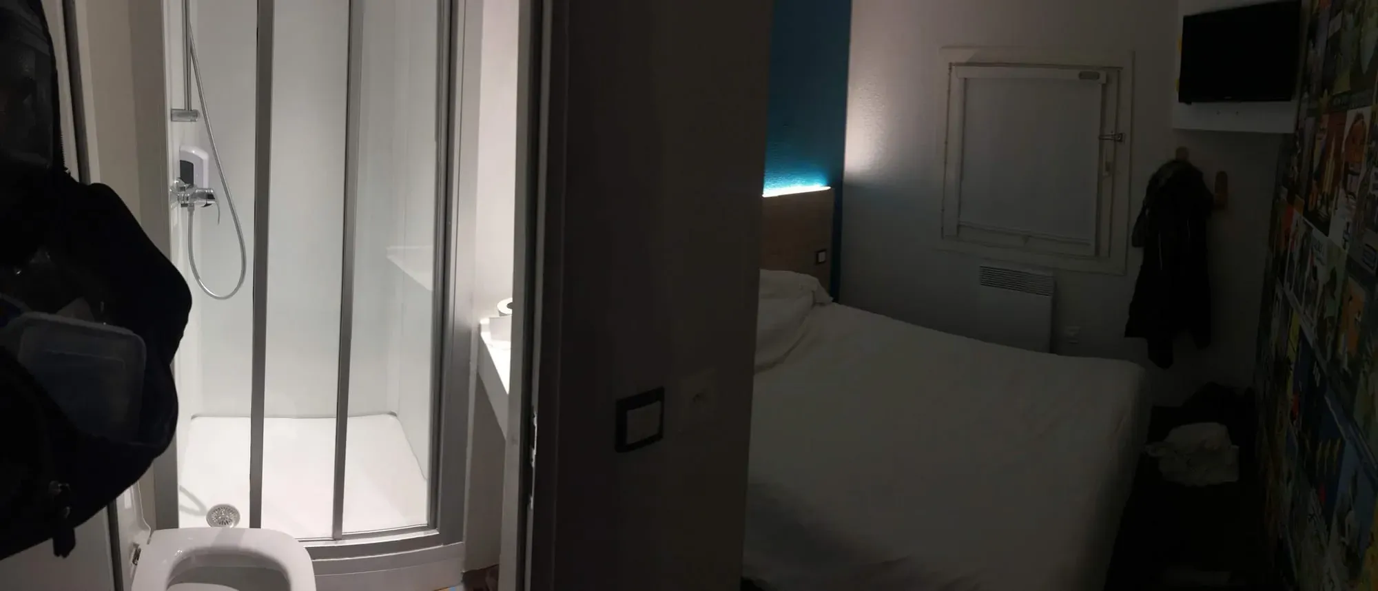 Modern hotel room interior with bed, shower, and ambient blue lighting