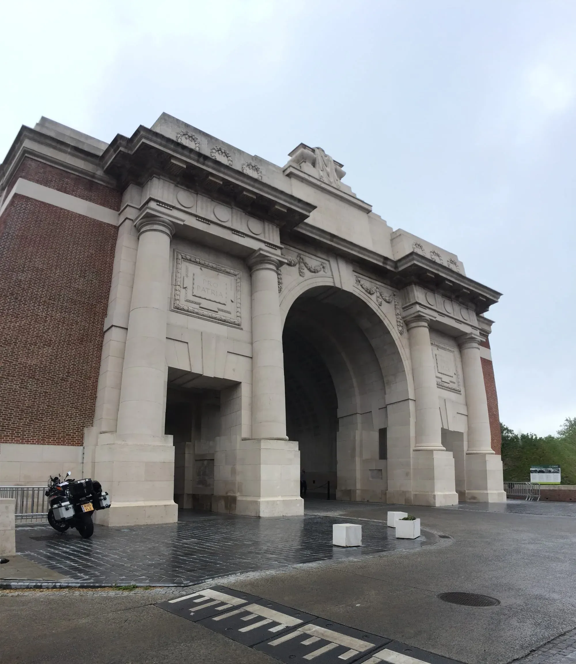 Historic stone memorial arch gate with motorcycle parked in front