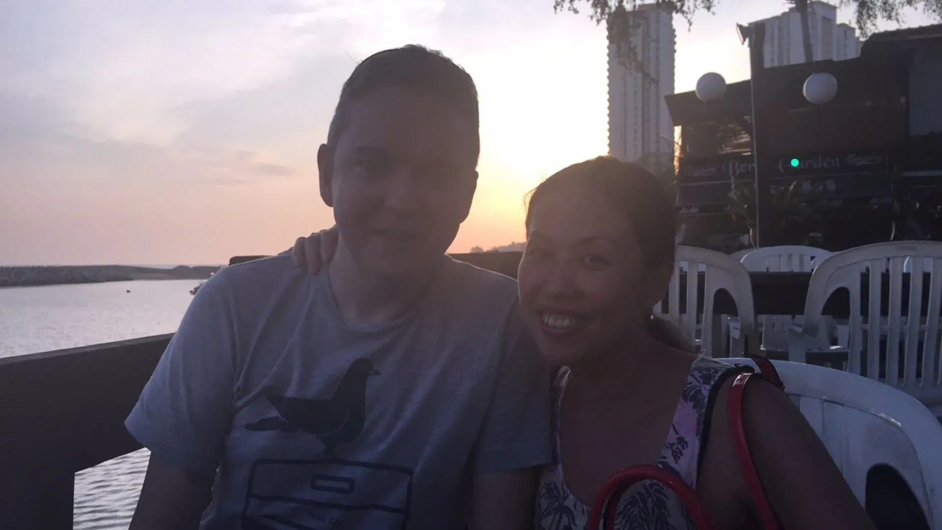 Two people posing together at waterfront during golden hour sunset