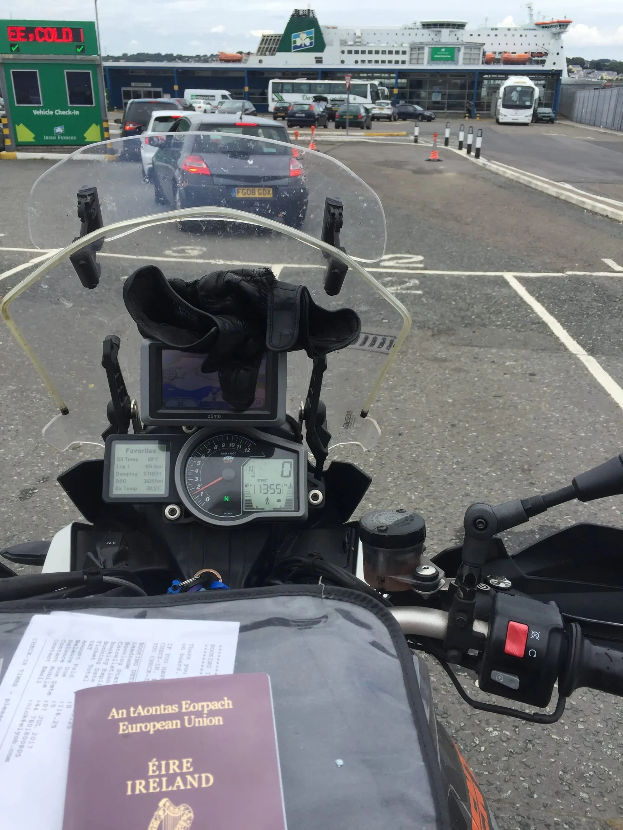 Motorcycle dashboard view at ferry terminal with Irish passport visible