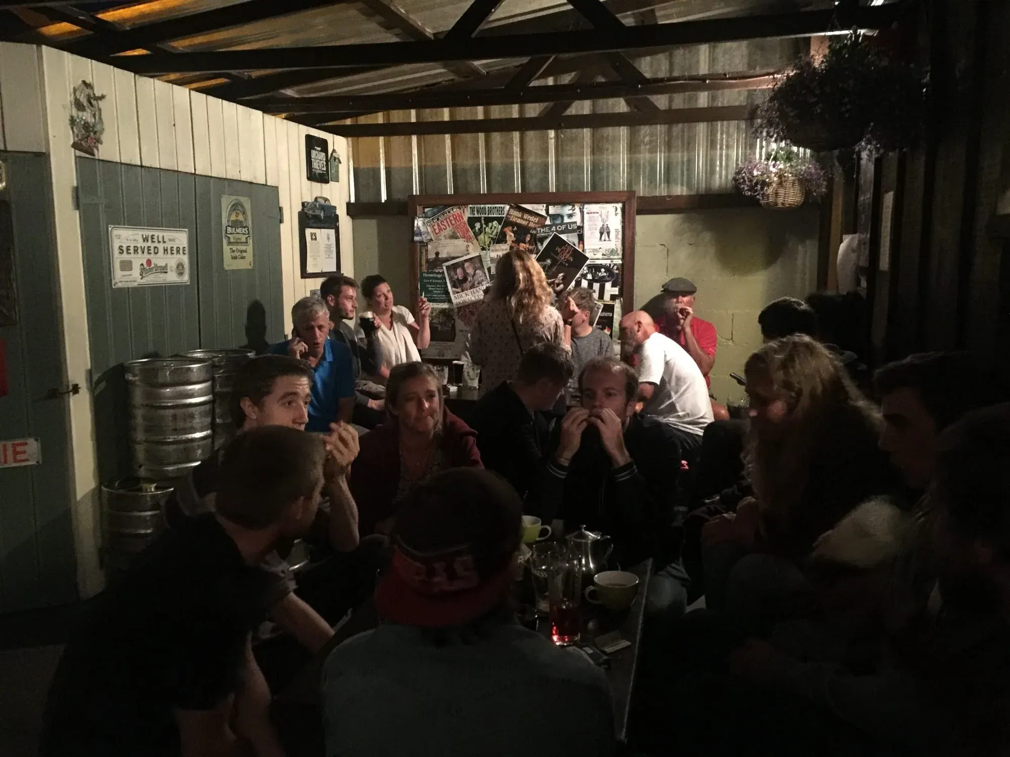 Crowded interior of rustic Irish pub with people gathered around wooden beams