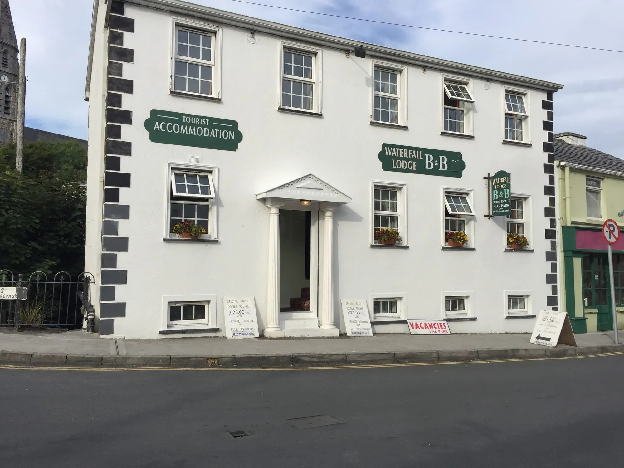 White Waterfall Lodge B&B building with green signage and flower boxes