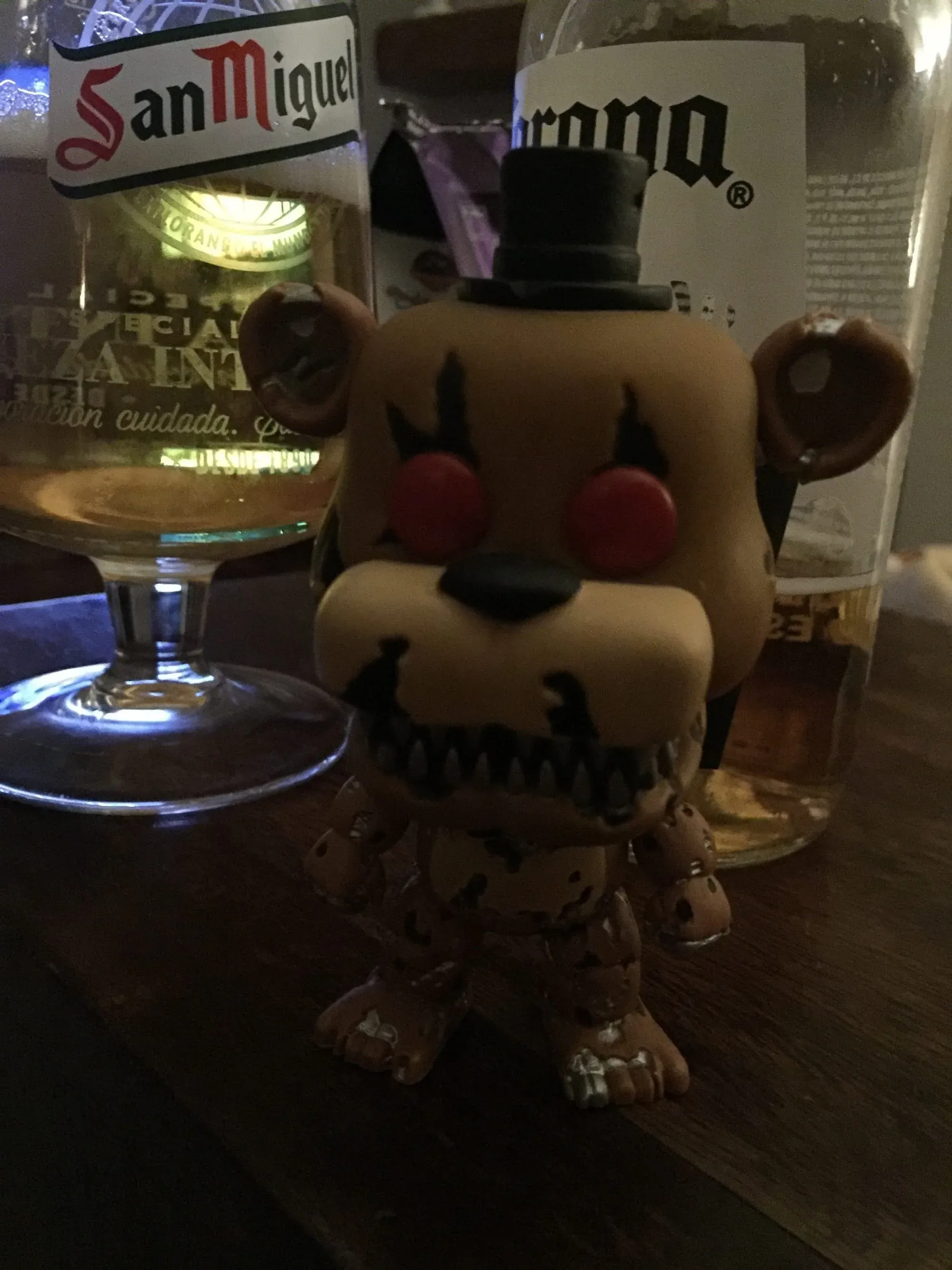 Novelty beer figurine with San Miguel and Corona bottles at bar counter