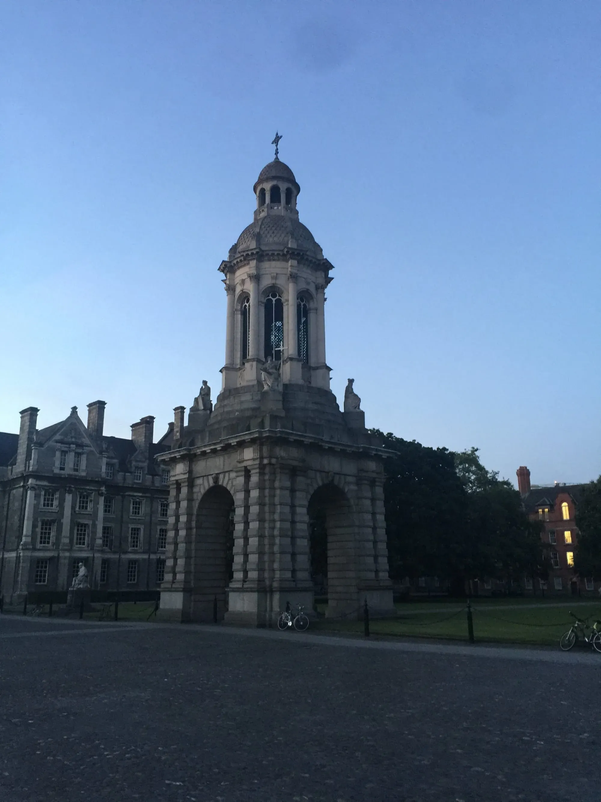 Bell tower at Trinity College Dublin campus at dusk with surrounding buildings