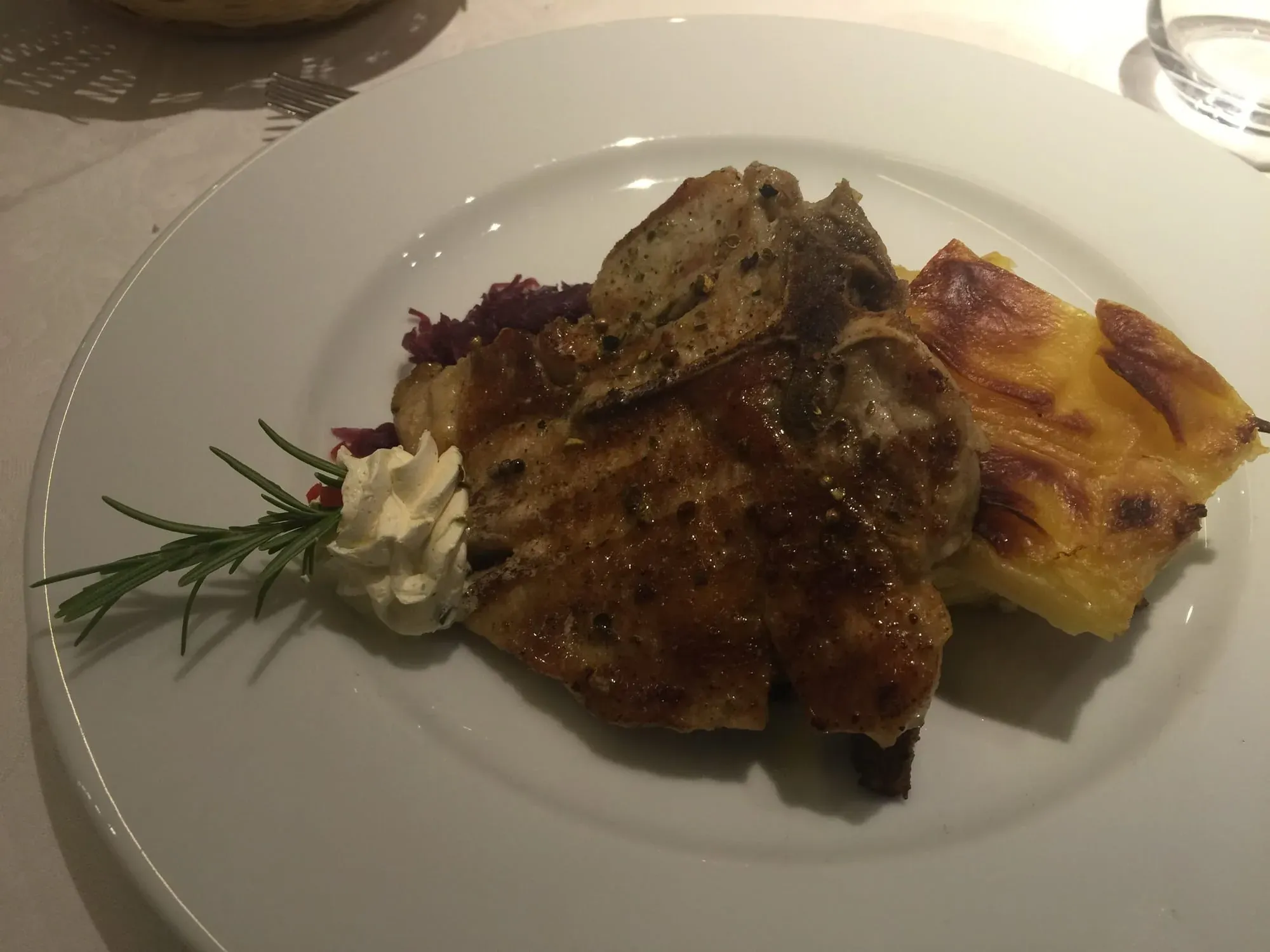 Gourmet plated meat dish with potato gratin and roasted vegetables on white plate