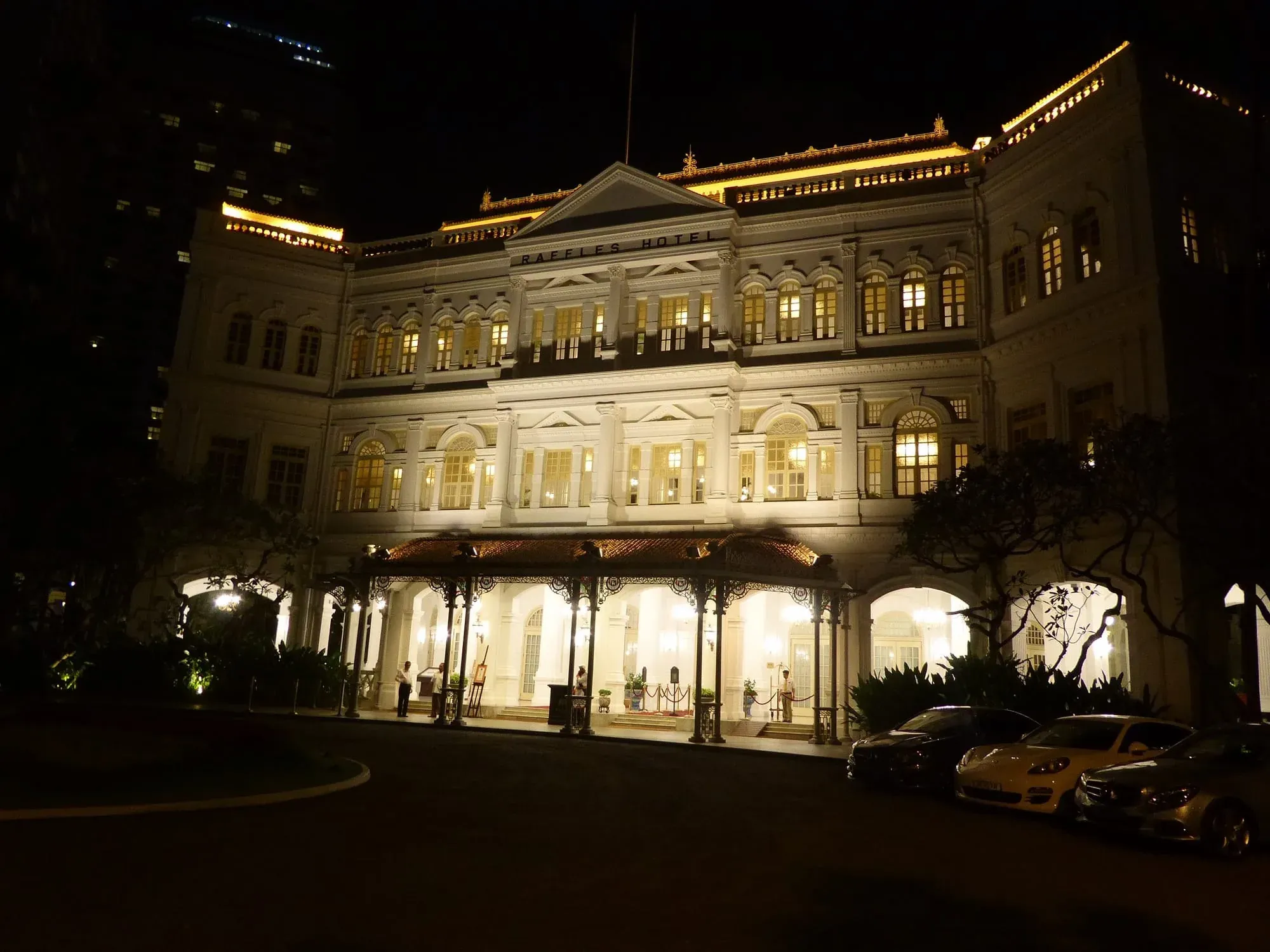 Illuminated Raffles Hotel colonial building at night with elegant architecture