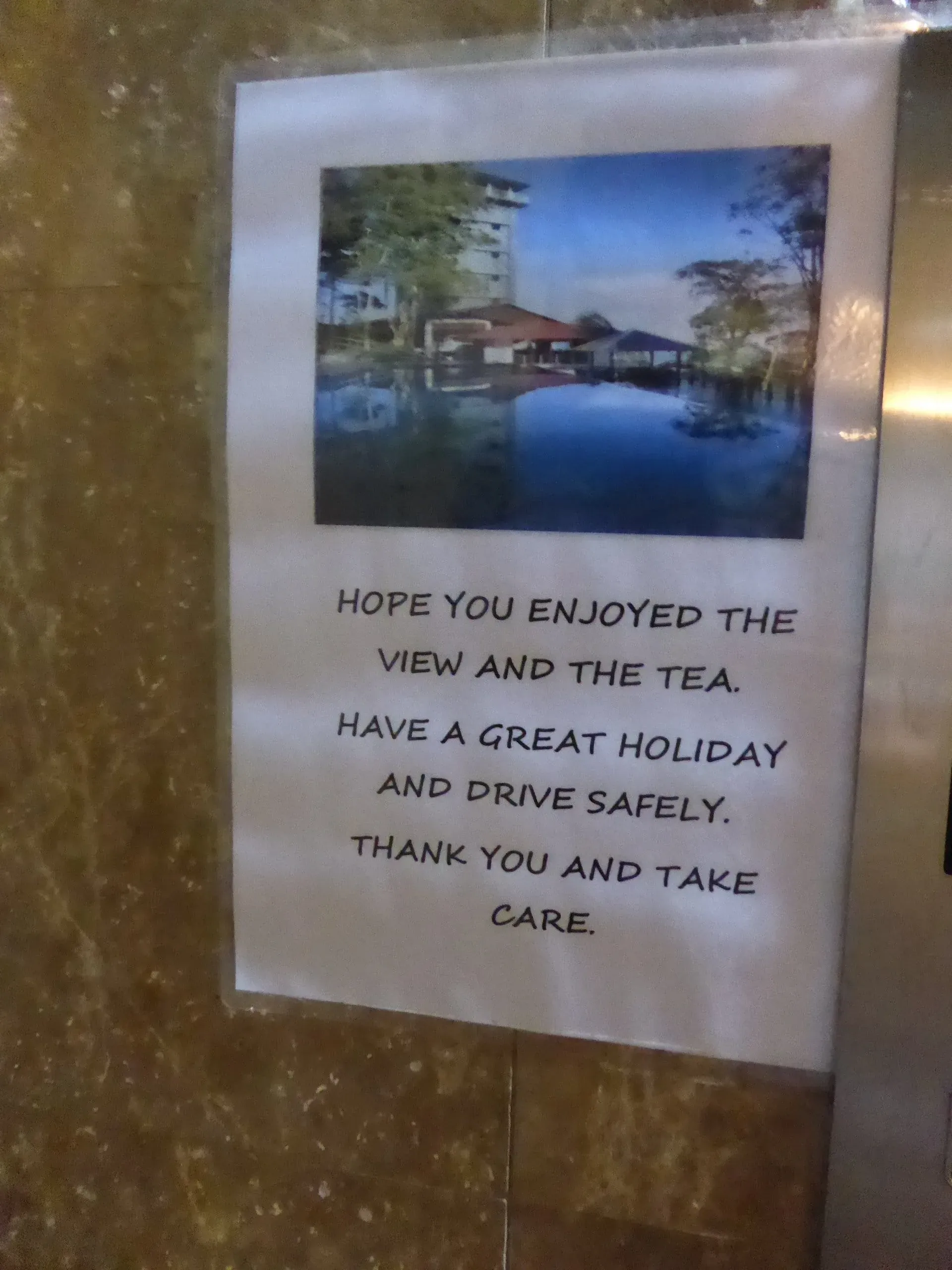 Farewell note with scenic riverside building photo on accommodation wall