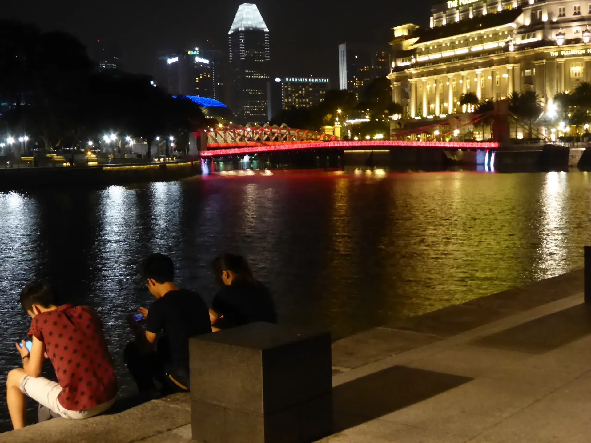 Red-lit bridge over water at night, Downtown Core Singapore