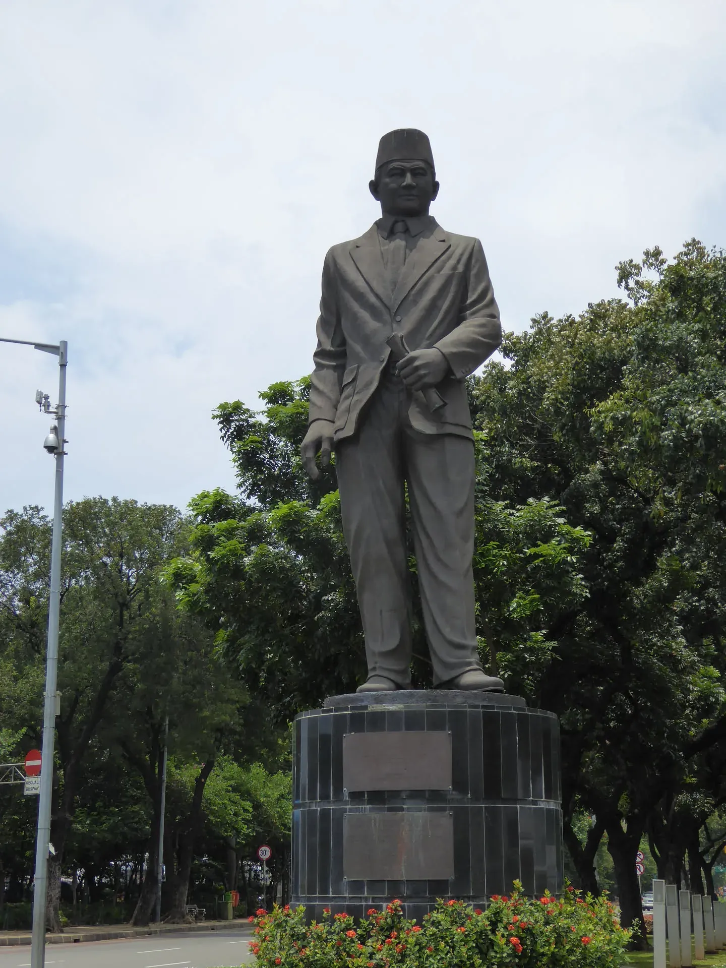 Tall statue of man in coat and hat in park