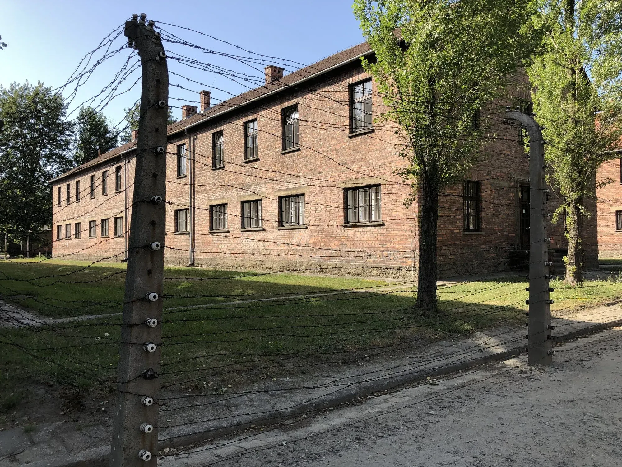 Barbed wire fence in front of brick building with windows