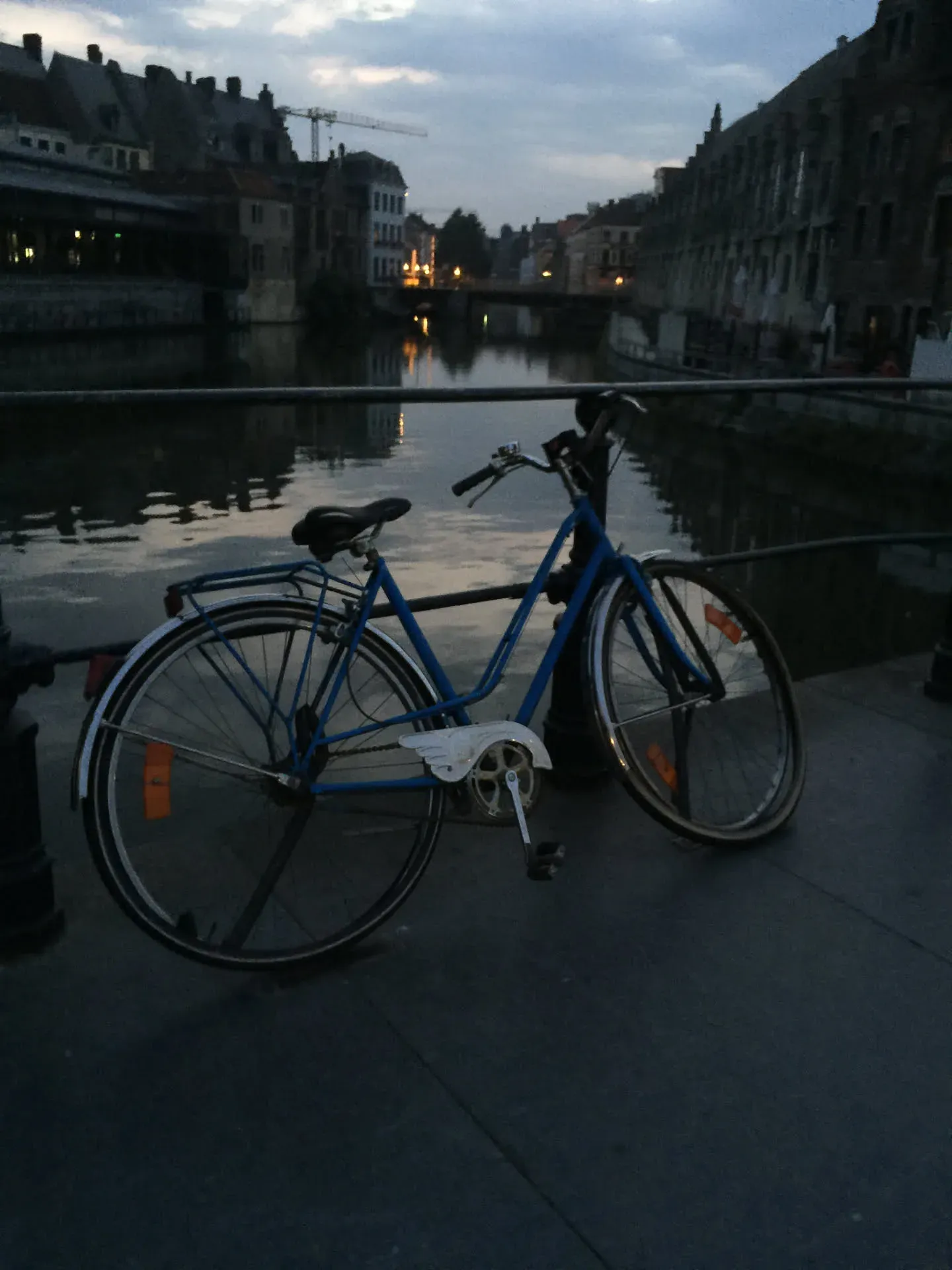 Blue bike parked by canal at dusk, Ghent