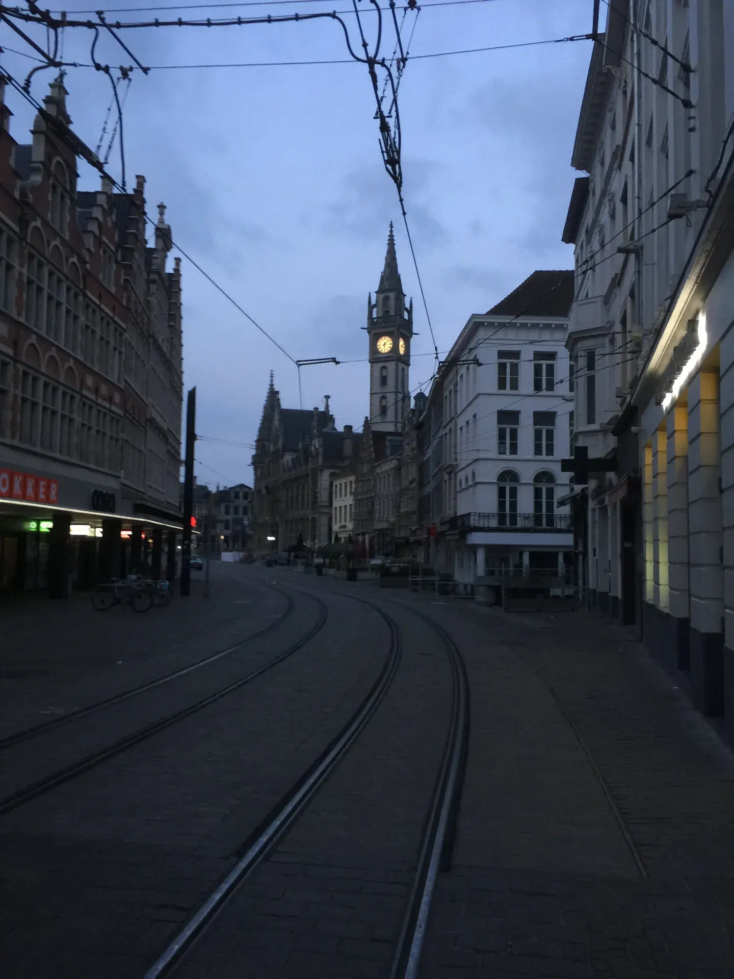 Tram tracks and clock tower in Ghent at dusk