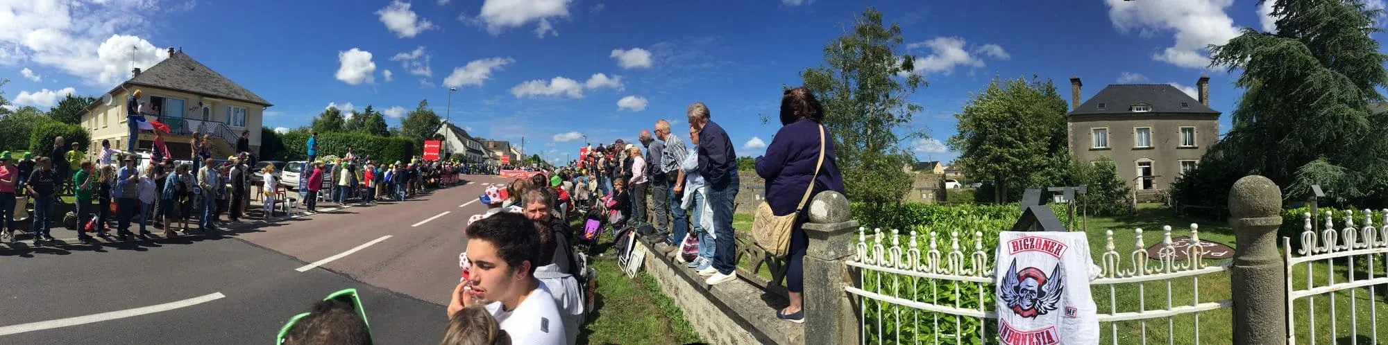 Large outdoor crowd gathered along rural road during daytime event